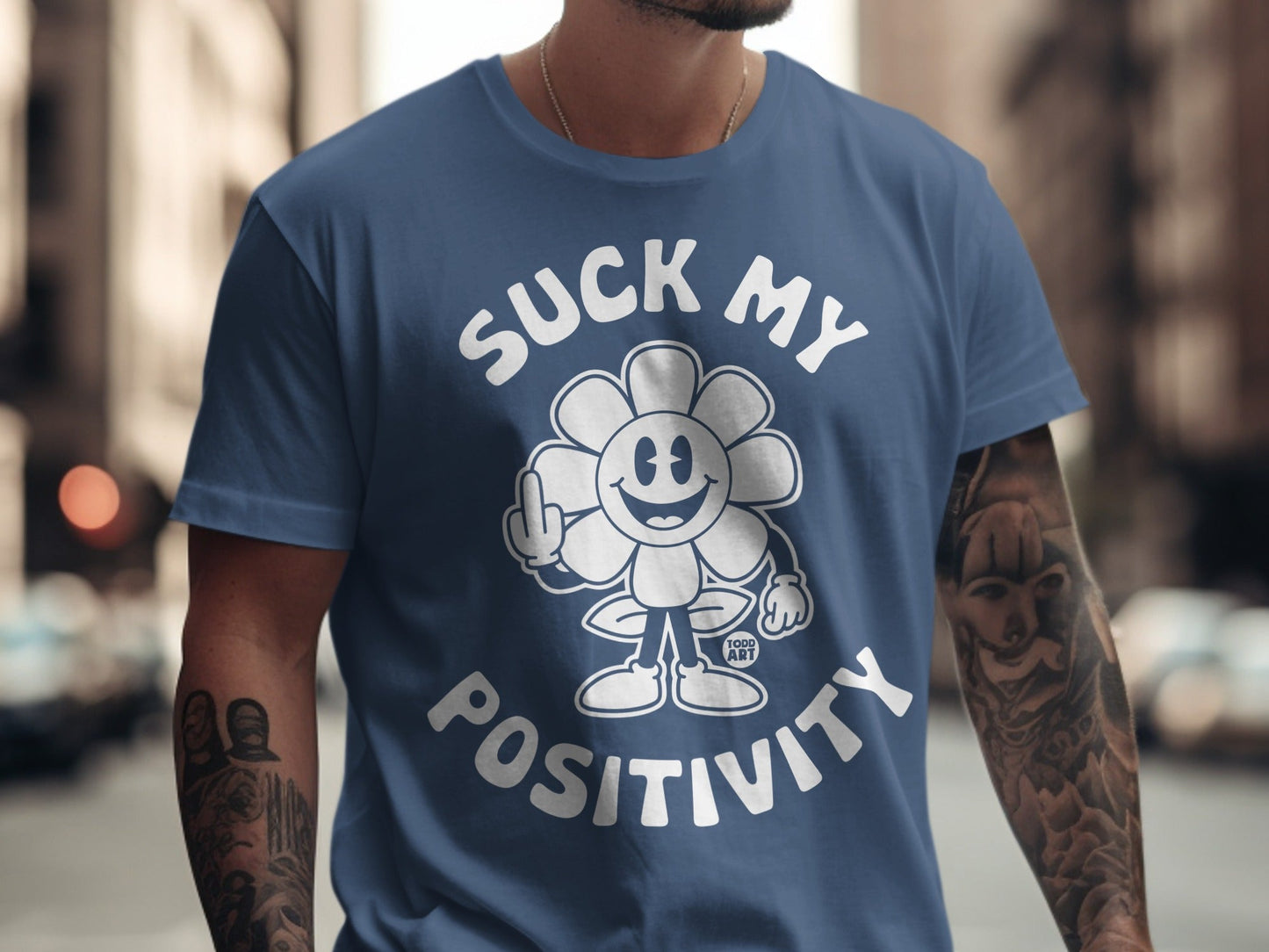 Navy blue t-shirt with a cartoon flower saying "Suck My Positivity" and a middle finger.