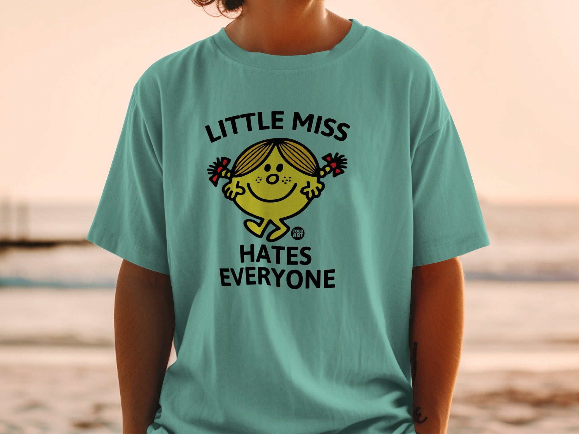 Teal t-shirt with "Little Miss Hates Everyone" and cartoon character graphic.