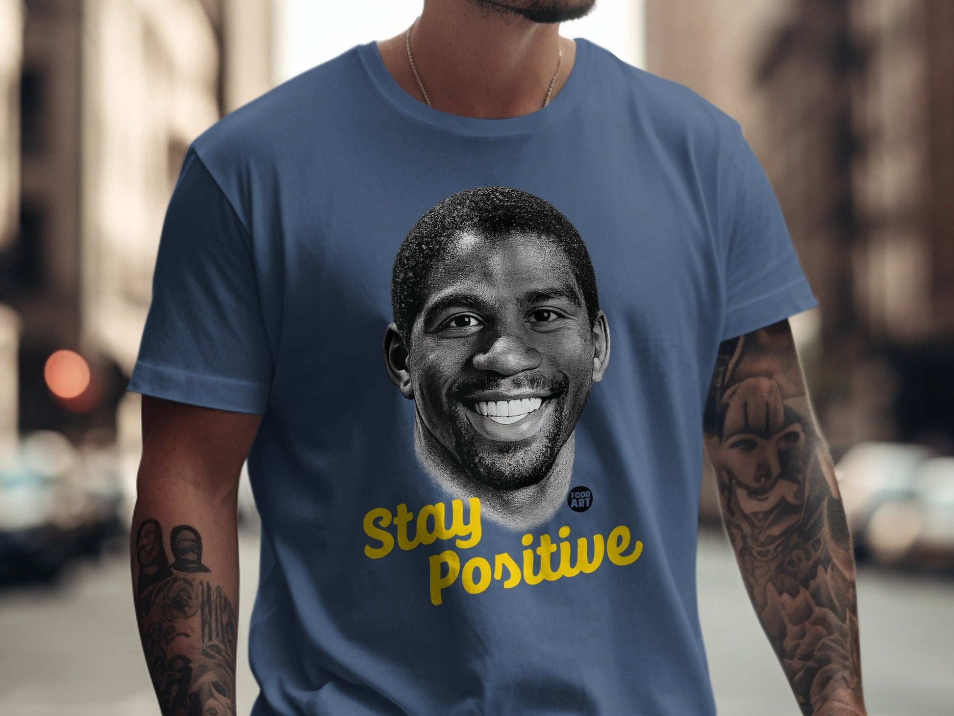 Magic Johnson portrait with "Stay Positive" text on a navy t-shirt.