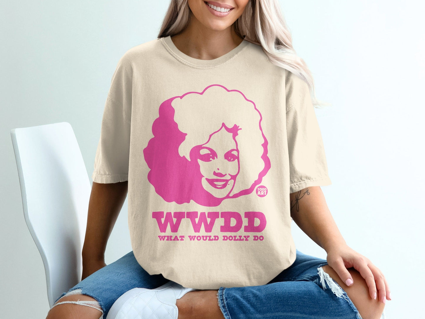 T-shirt with pink text "WWDD WHAT WOULD DOLLY" and silhouette of Dolly Parton.