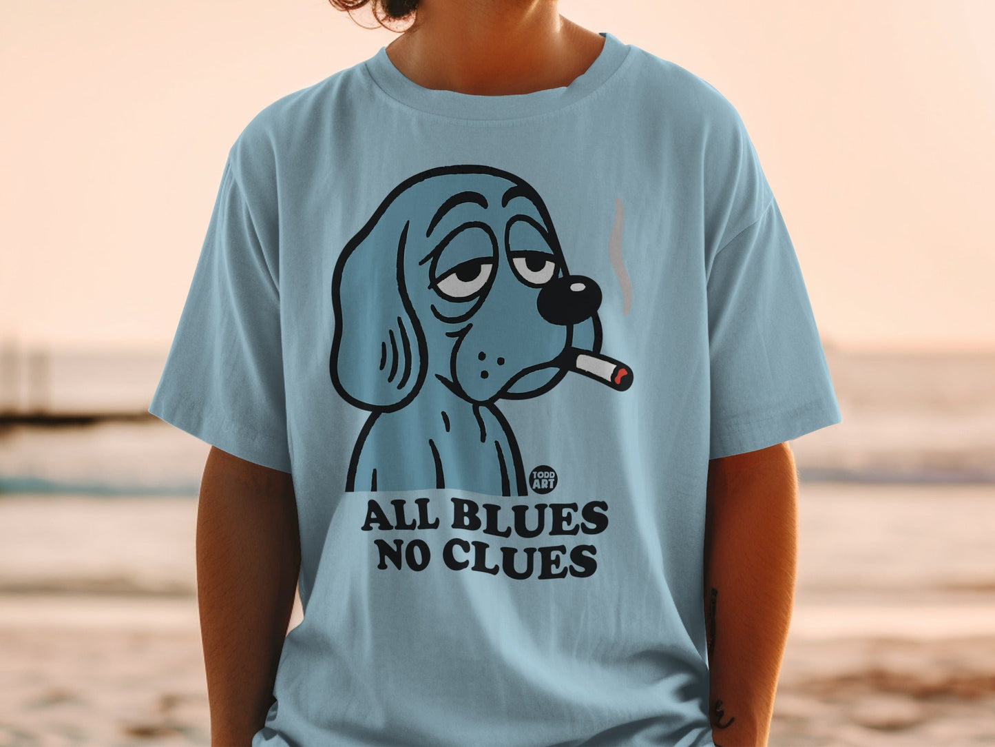 Light blue t-shirt with cartoon dog smoking cigarette, "ALL BLUES NO CLUES" text.