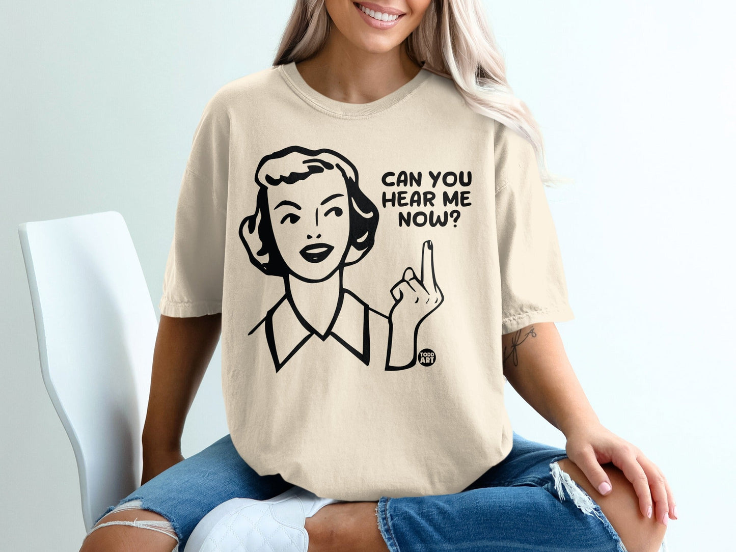 Woman in a cream t-shirt with text "CAN YOU HEAR ME NOW?".