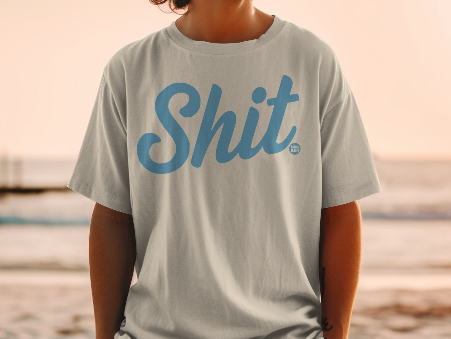 Light grey t-shirt with "Shit" in blue font and "Good Art" logo.
