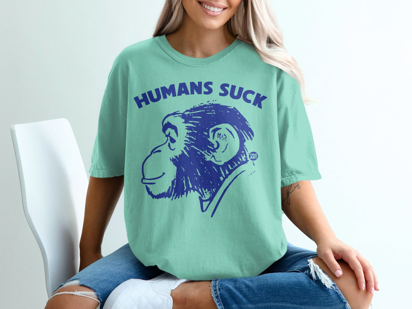 Mint green t-shirt with blue graphic of a monkey and text "HUMANS SUCK".