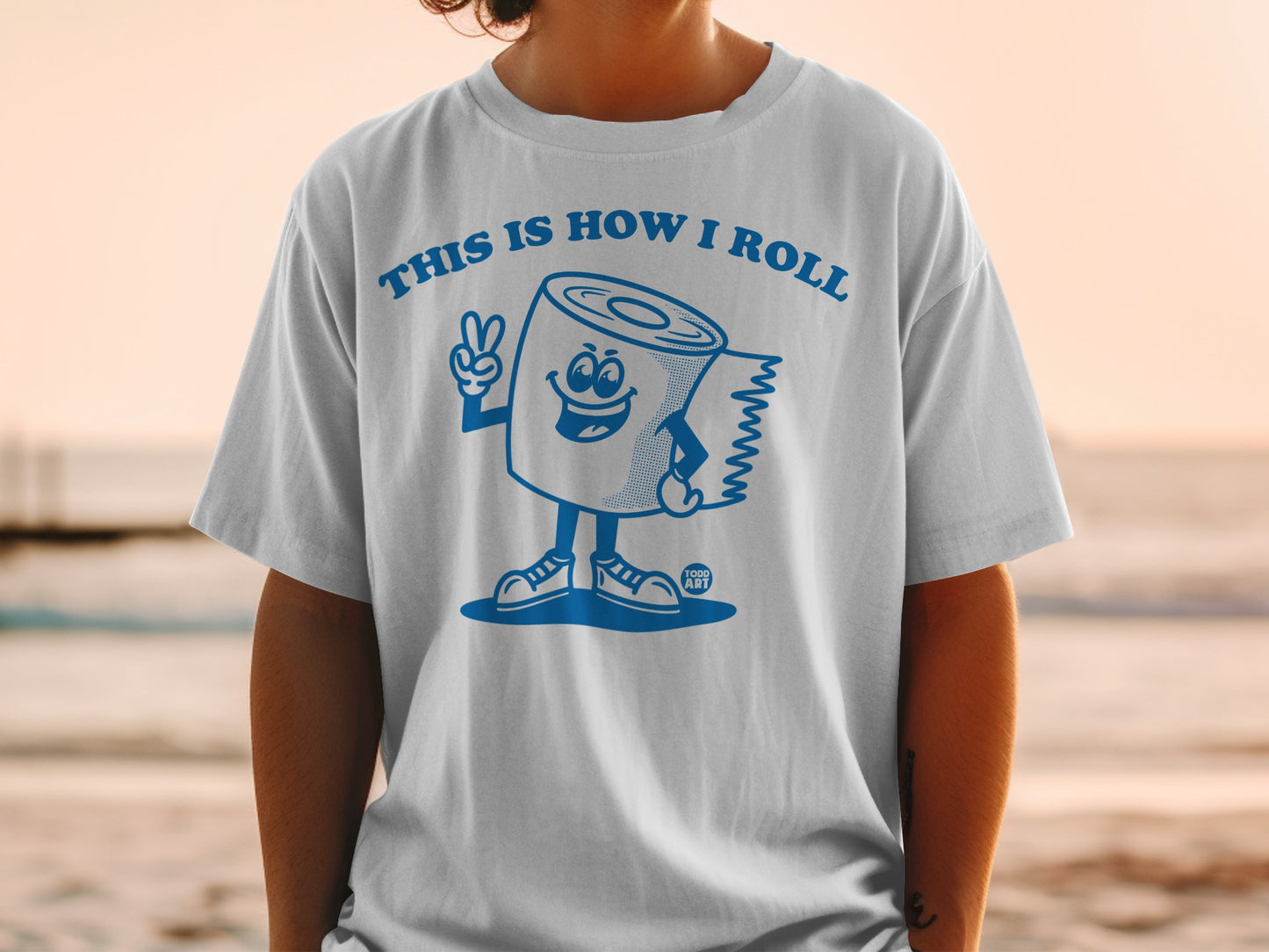 Cartoon toilet paper roll giving peace sign on white t-shirt.