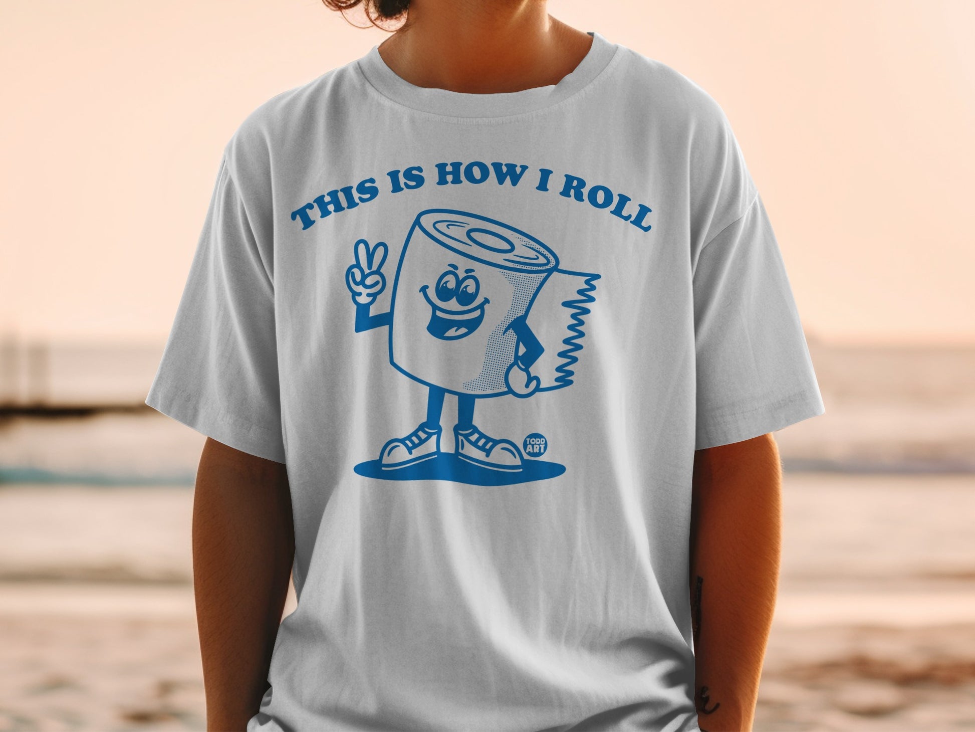 Cartoon toilet paper roll giving peace sign on white t-shirt.