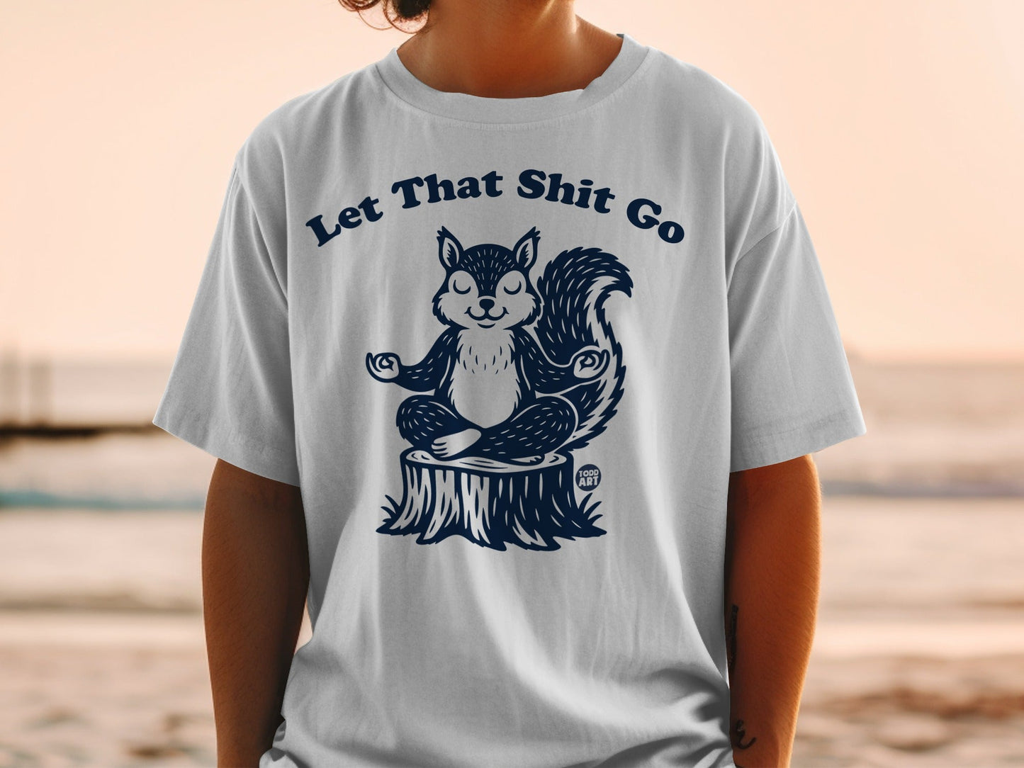T-shirt with meditating squirrel on a stump, text "Let That Shit Go".