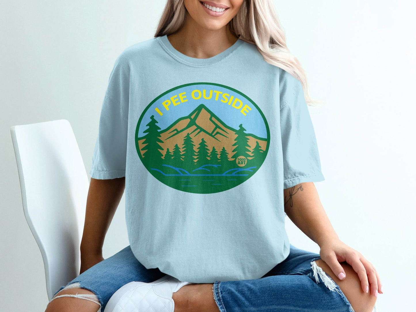 Light blue t-shirt with oval graphic of mountains, trees, and "I PEE OUTSIDE" text.