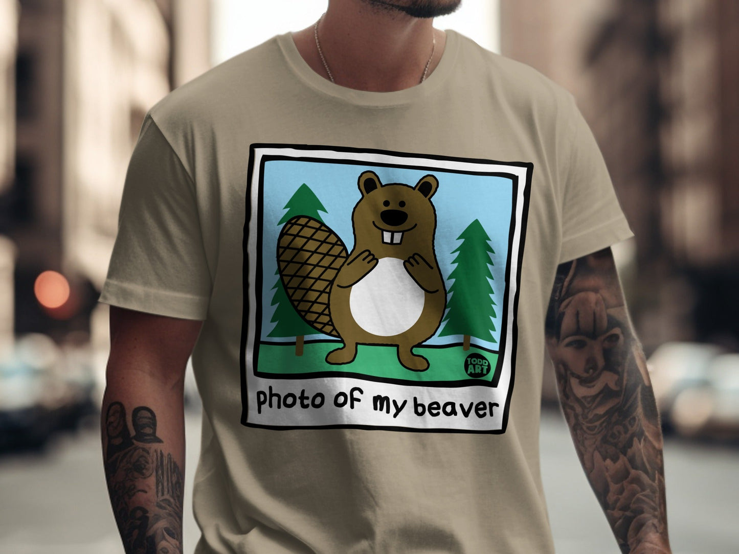Cartoon beaver with large tail and trees on a tan t-shirt.