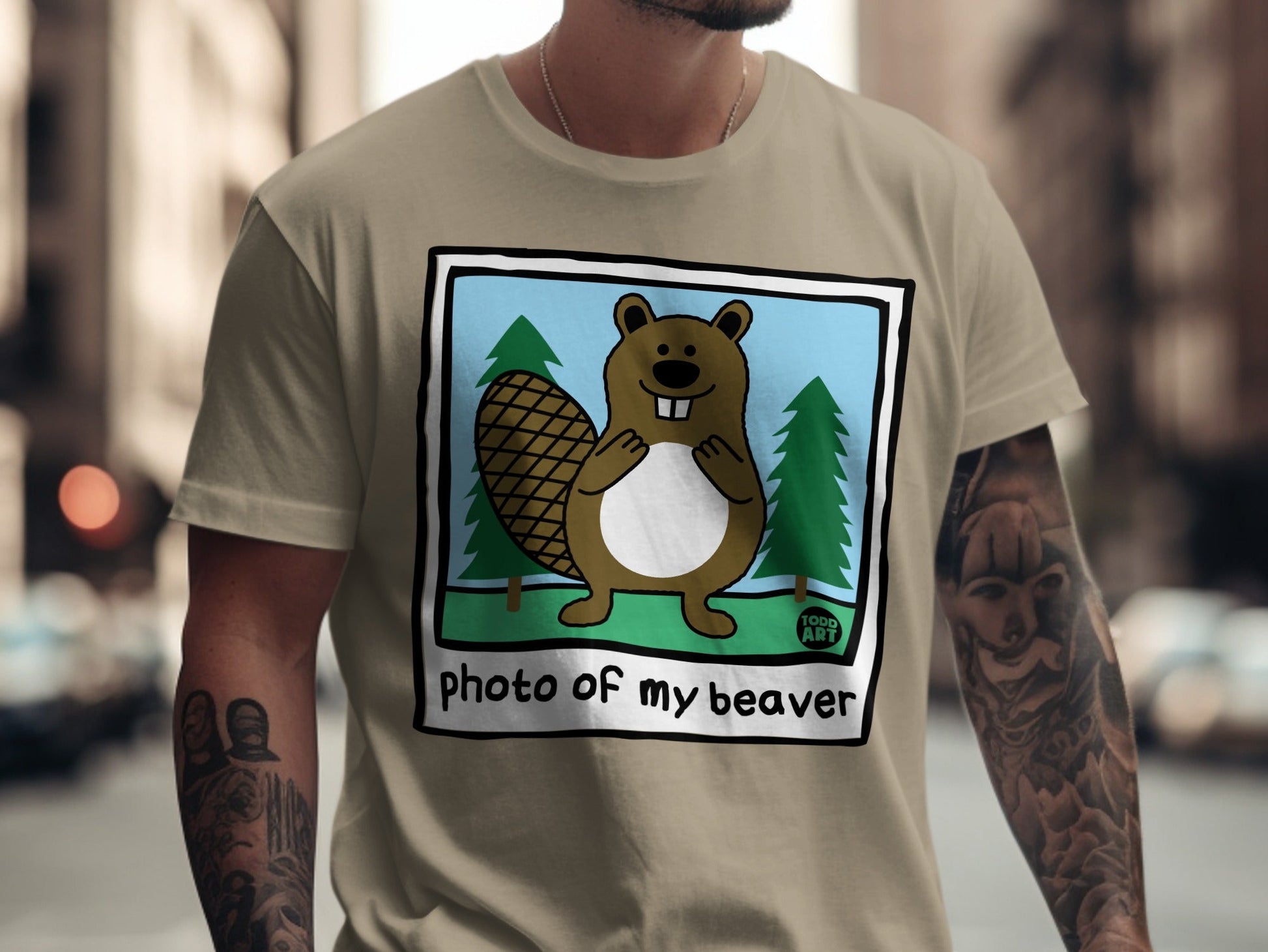 Cartoon beaver with large tail and trees on a tan t-shirt.