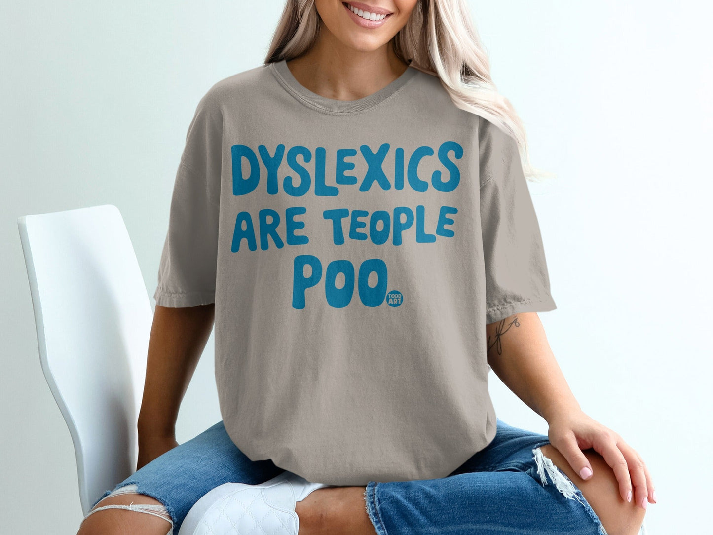 Taupe t-shirt with blue text "DYSLEXICS ARE TEOPOL POO ART".