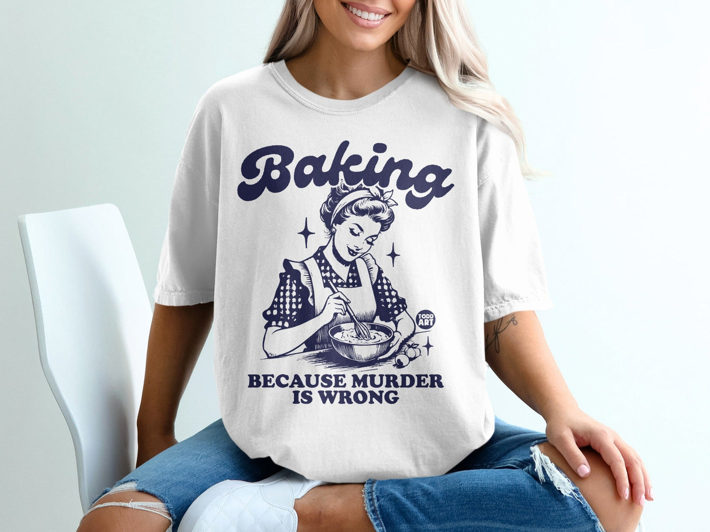 White t-shirt with "Baking because murder is wrong" and retro illustration.