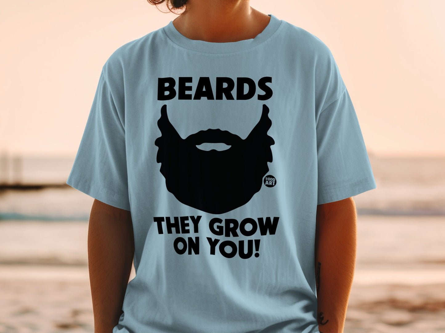 Light blue t-shirt with black beard graphic and text "BEARDS THEY GROW ON YOU!"