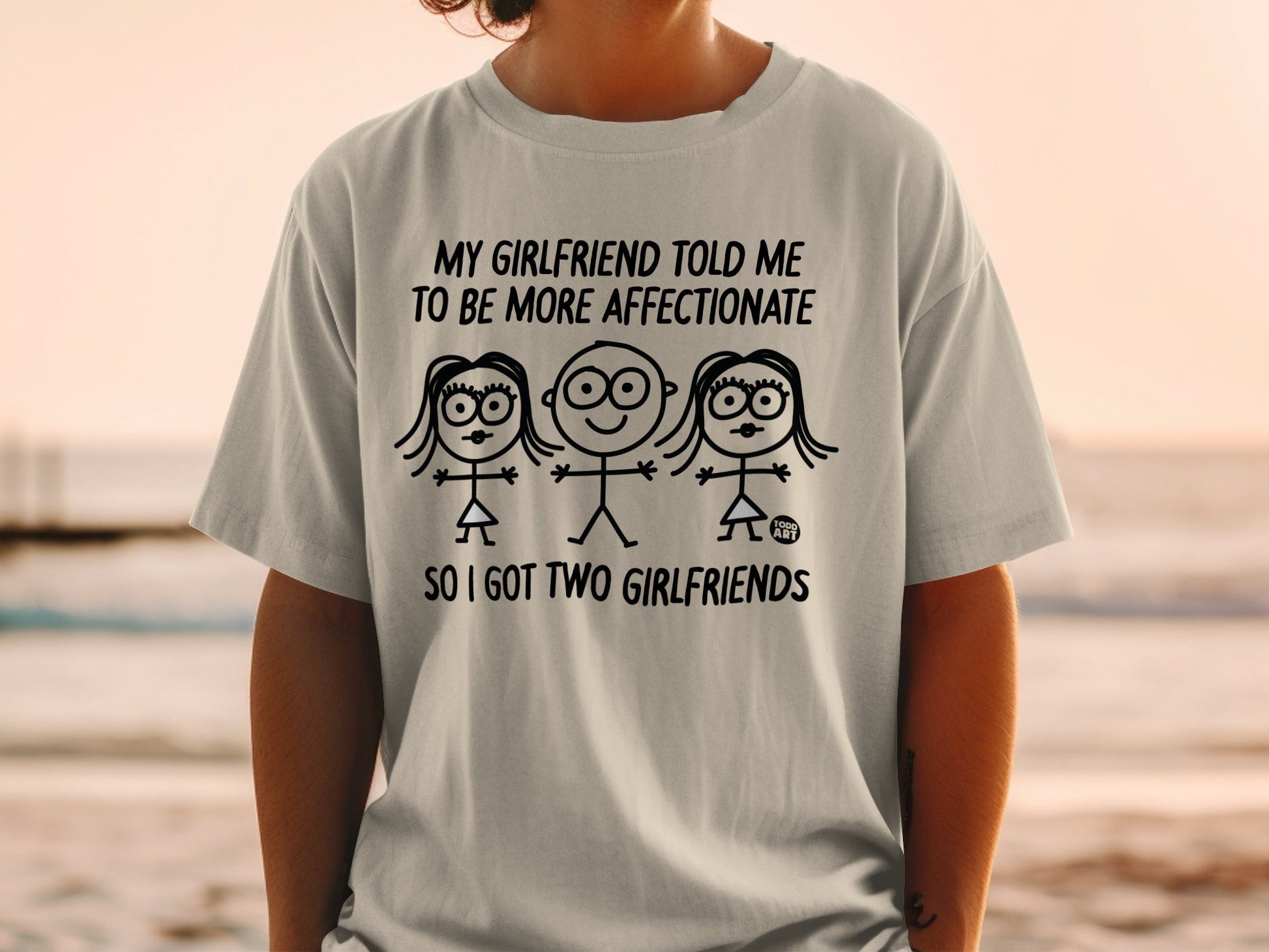 T-shirt with "My girlfriend told me to be more affectionate so I got two girlfriends" text and stick figures.