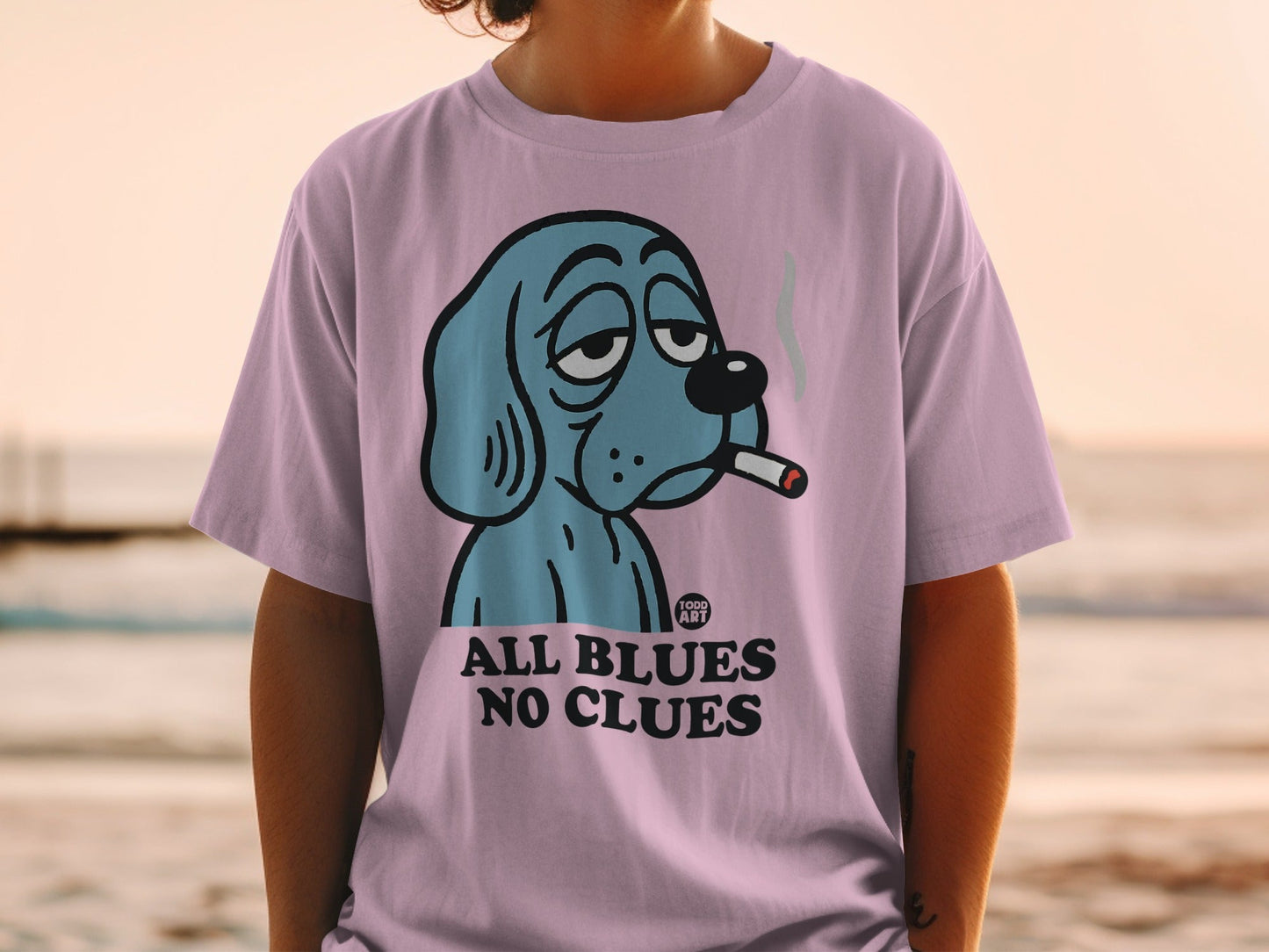 Pink t-shirt with cartoon blue dog smoking, "ALL BLUES NO CLUES" text.