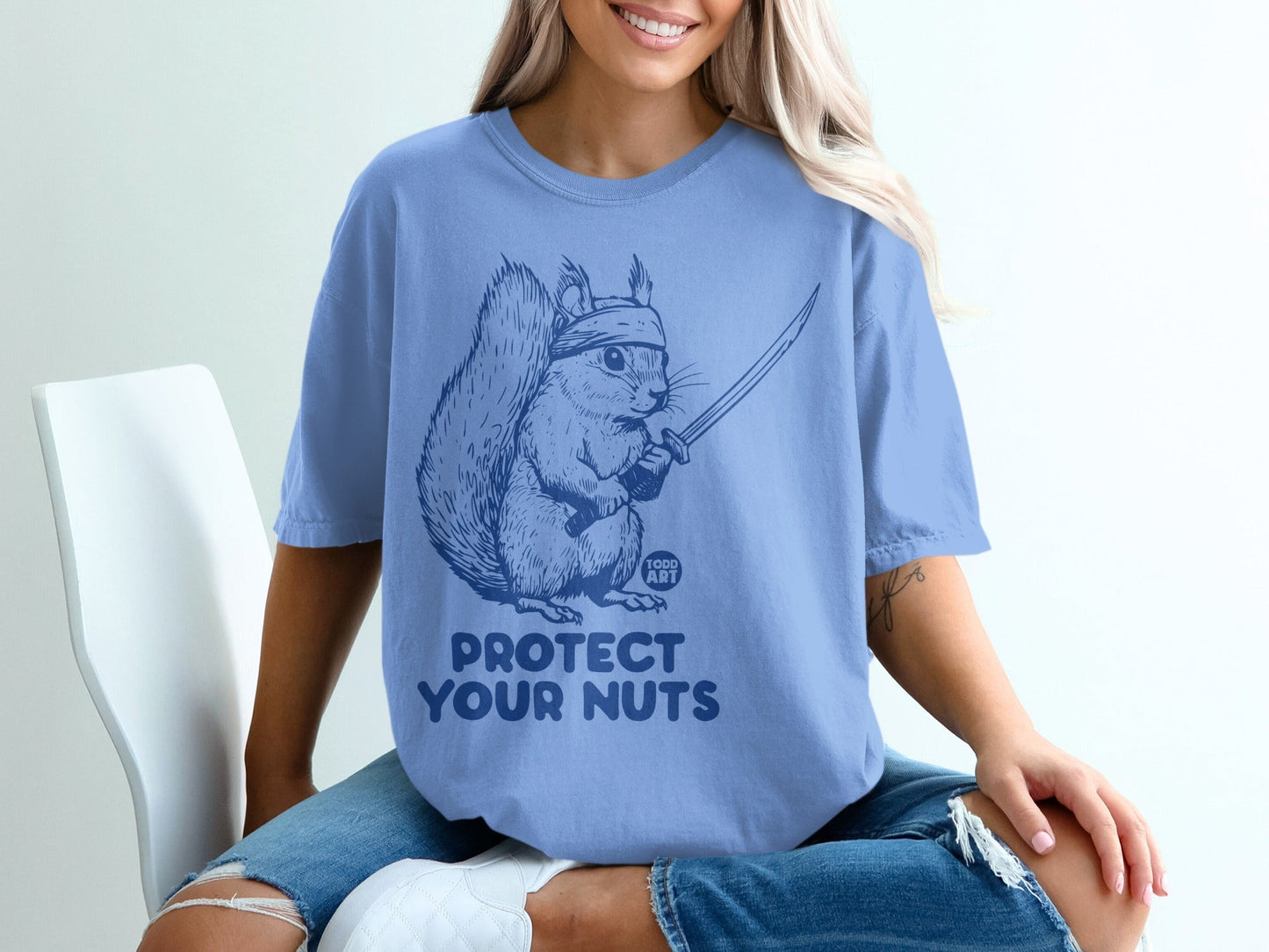 Blue t-shirt with a squirrel holding a sword, text "PROTECT YOUR NUTS".