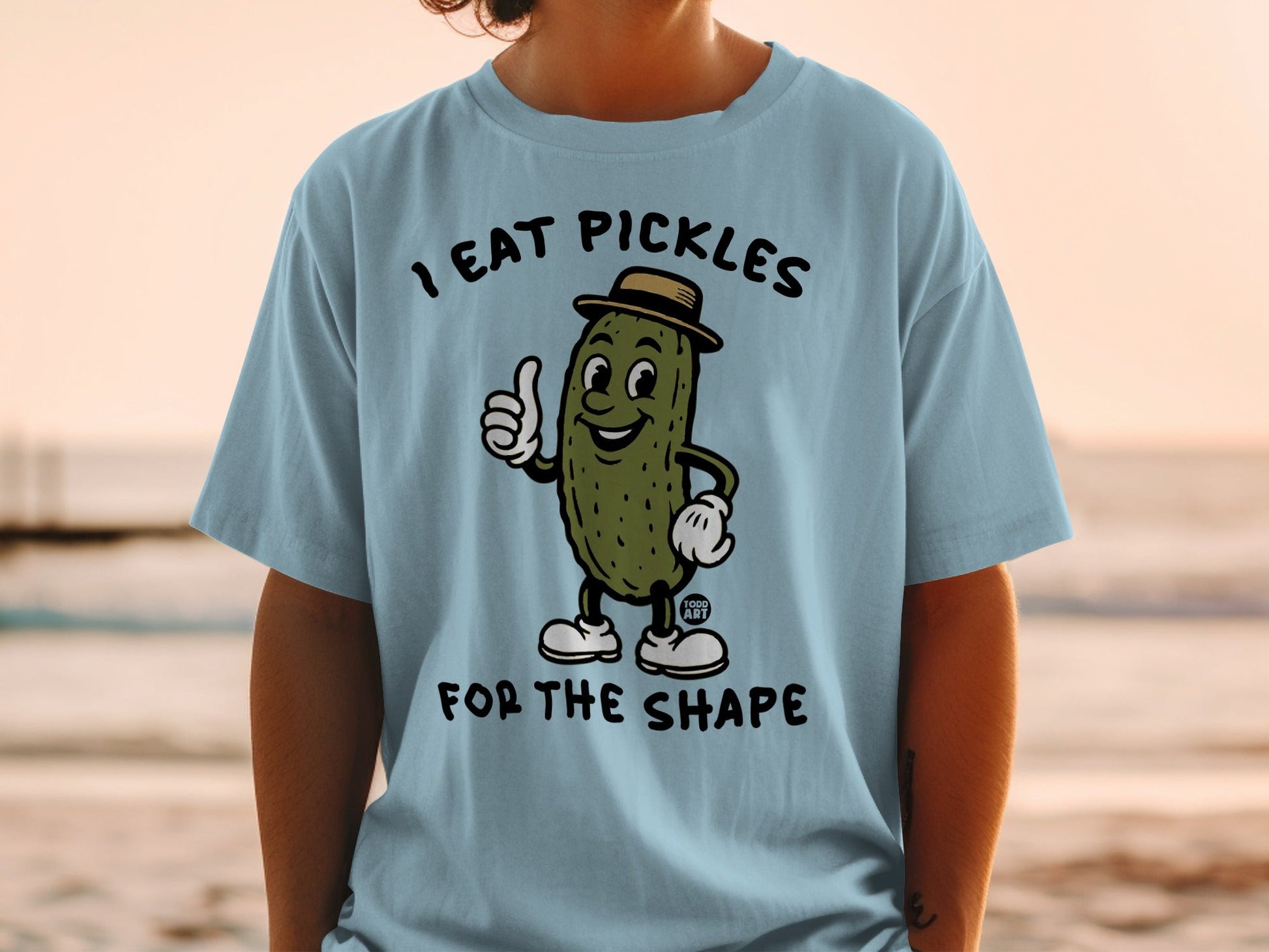 Light blue t-shirt with cartoon pickle wearing a hat giving a thumbs up.