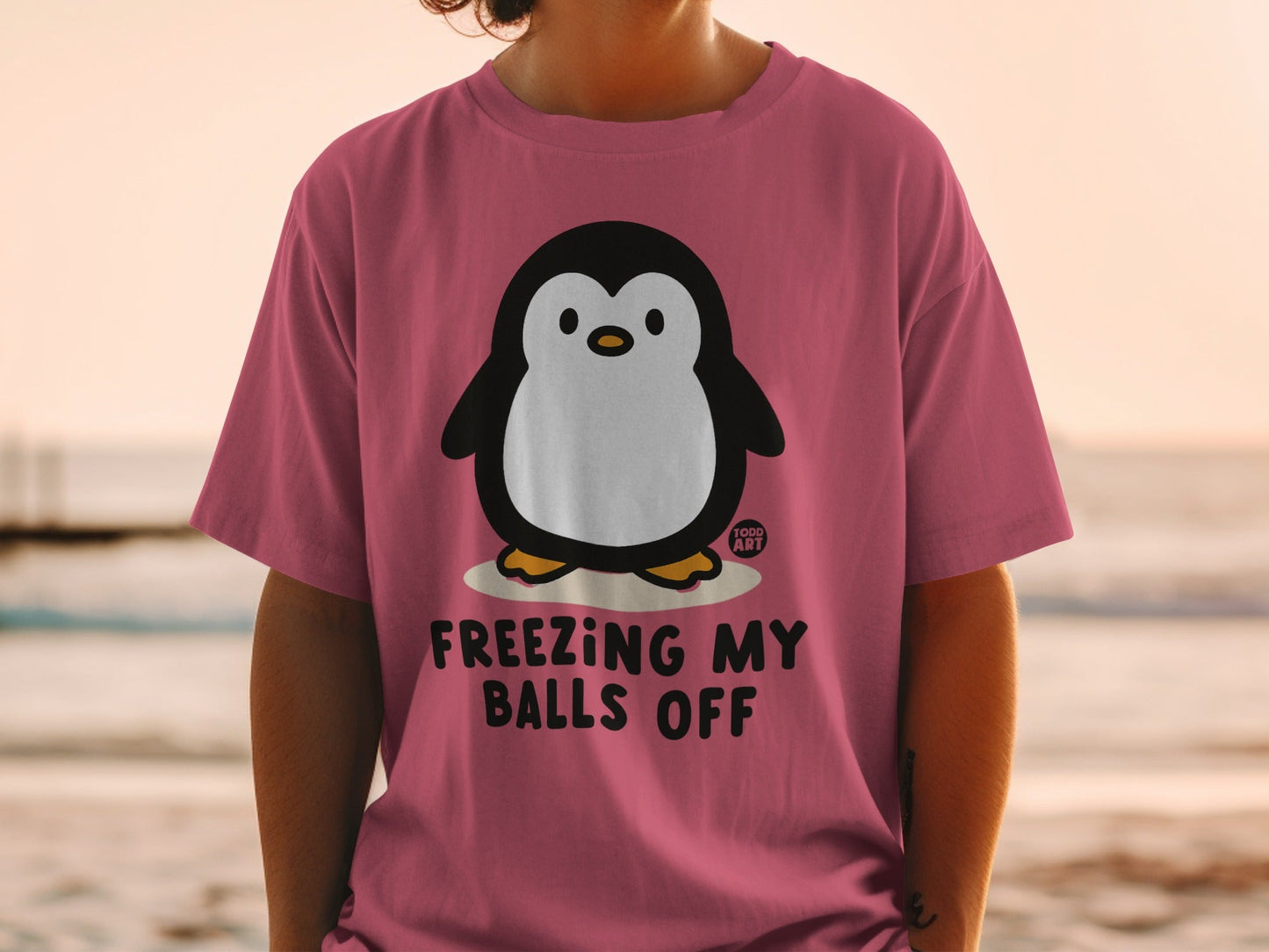 Pink t-shirt with a cartoon penguin and "Freezing My Balls Off" text.