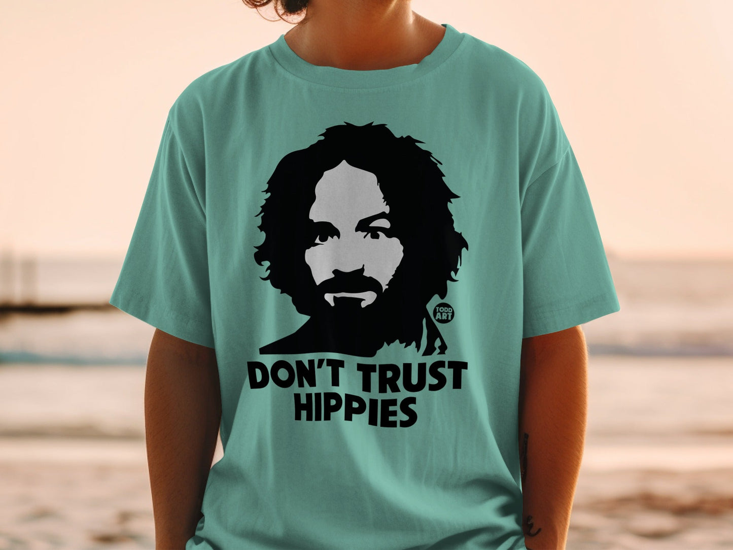 Teal t-shirt with black graphic of Charles Manson and "DON'T TRUST HIPPIES".