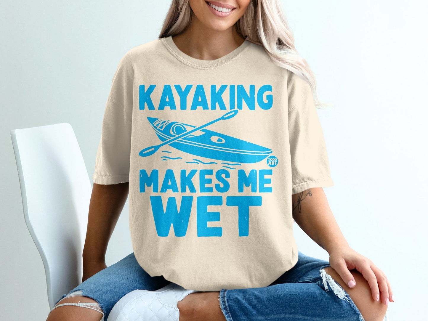 Cream t-shirt with "Kayaking Makes Me Wet" and kayak graphic.