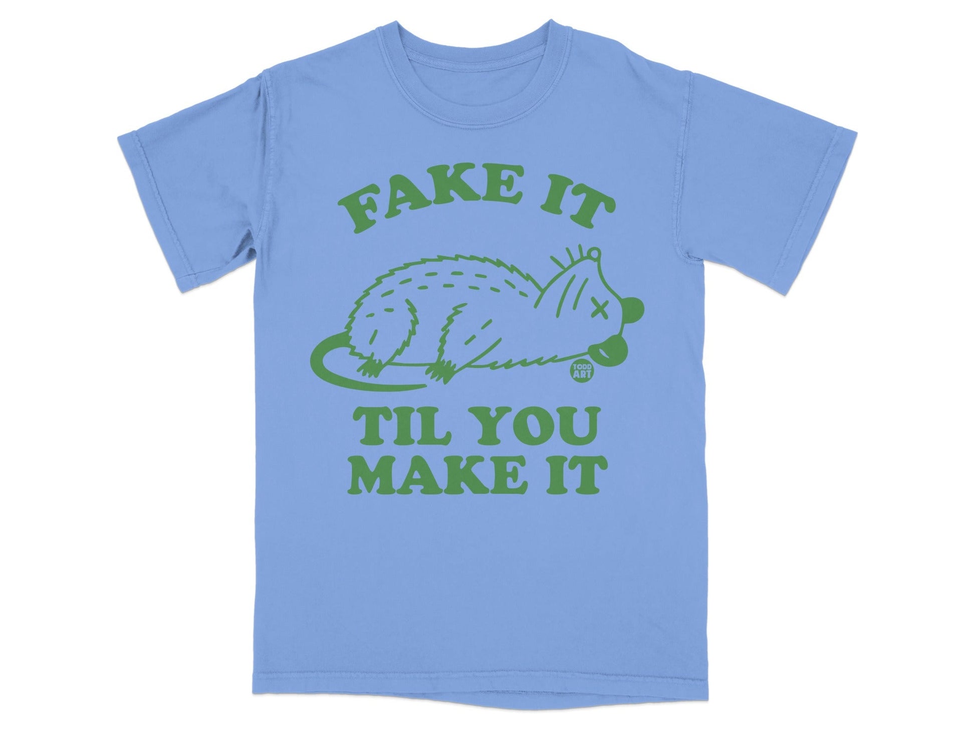 Light blue t-shirt with a green graphic of a possum and text "FAKE IT TIL YOU MAKE IT".