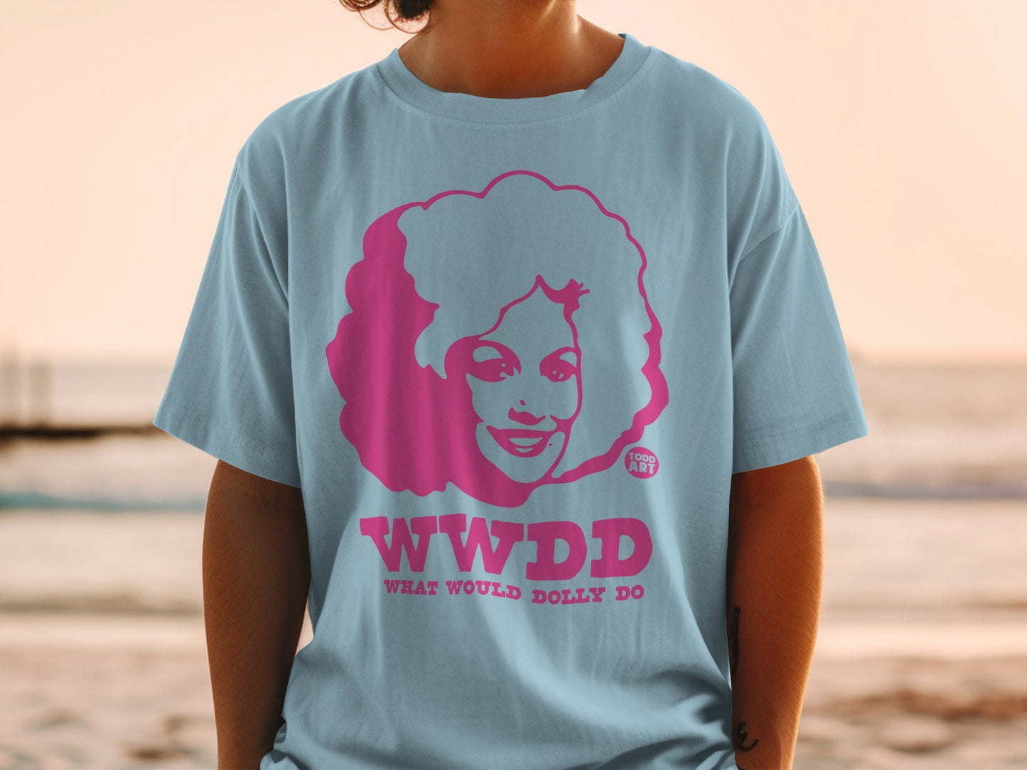 Light blue t-shirt featuring pink "WWDD WHAT WOULD DOLLY DO" text and Dolly Parton portrait.
