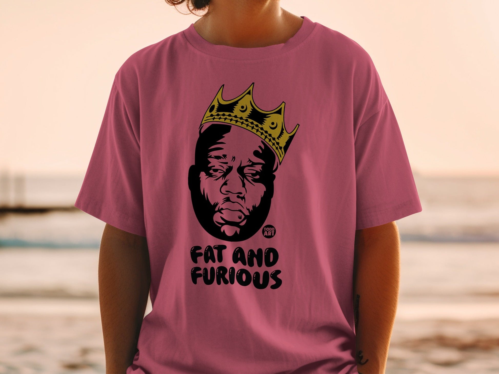 Pink t-shirt with black graphic of crowned man and text "FAT AND FURIOUS".
