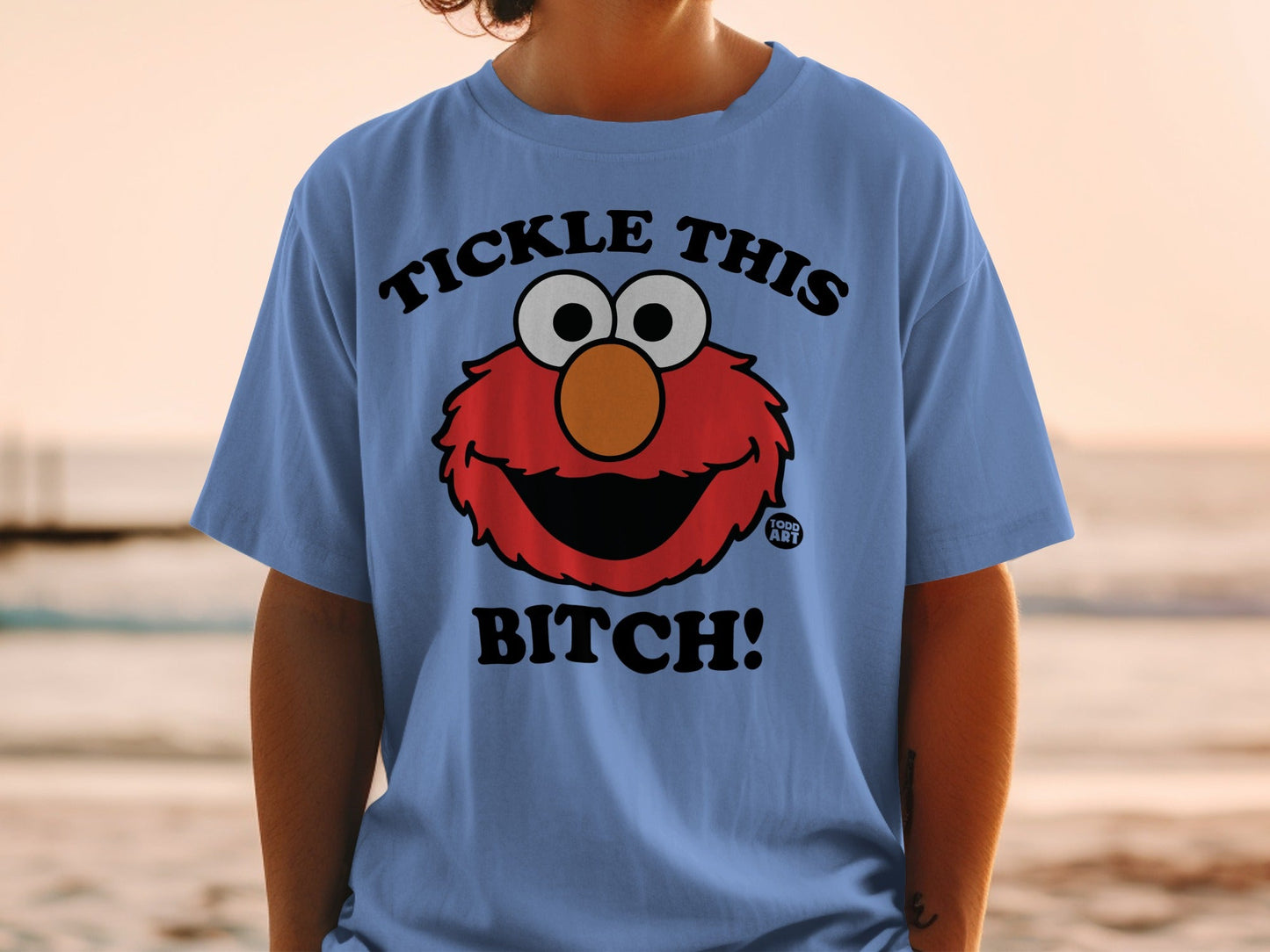 Elmo's face with text "Tickle This Bitch!" on a blue t-shirt.