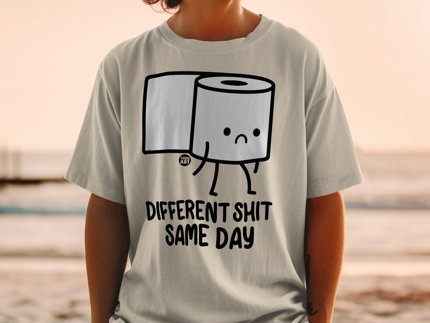 T-shirt with cartoon toilet paper roll and text "Different Shit Same Day".