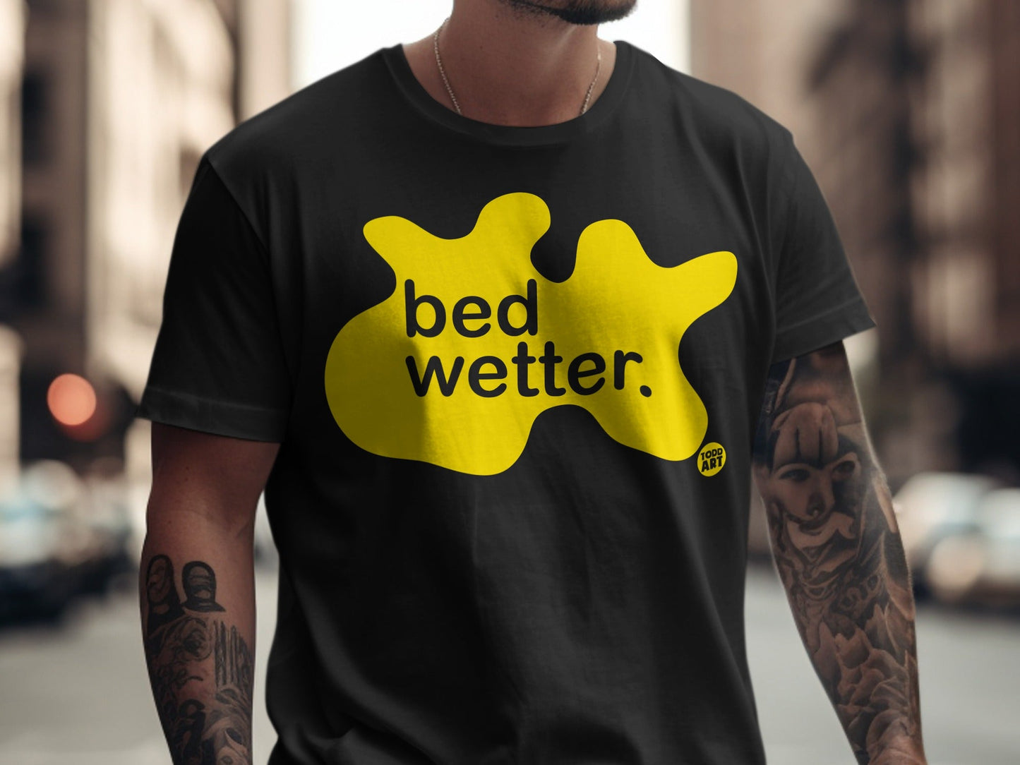 Black t-shirt with yellow blob graphic and "bed wetter" text.