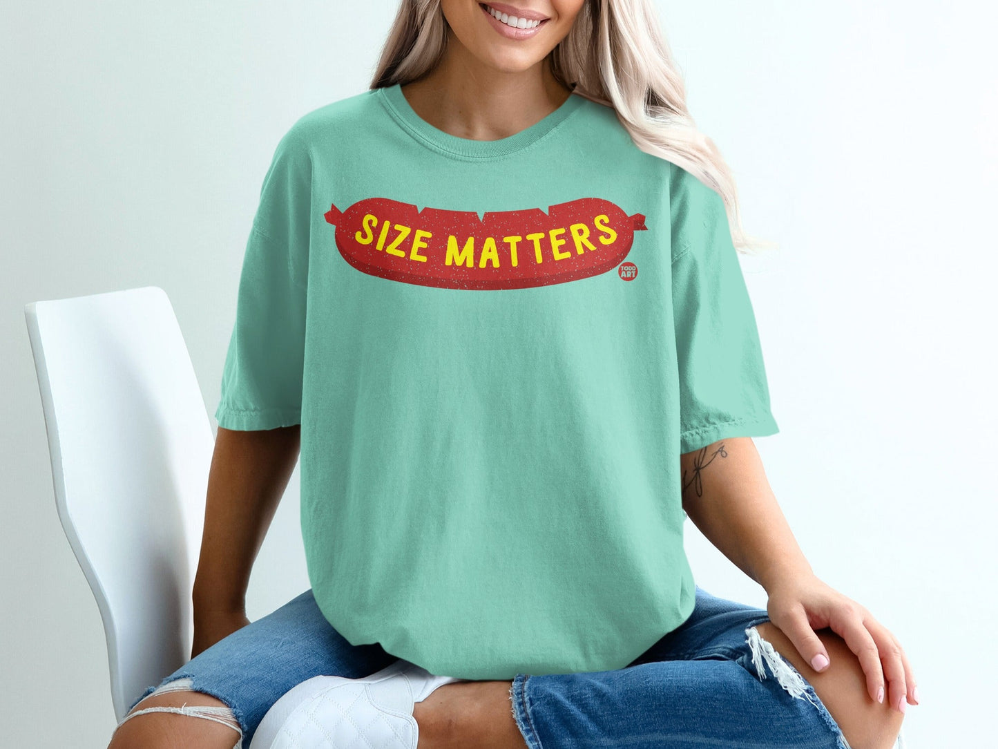 Mint green t-shirt with red "SIZE MATTERS" text on a sausage graphic.