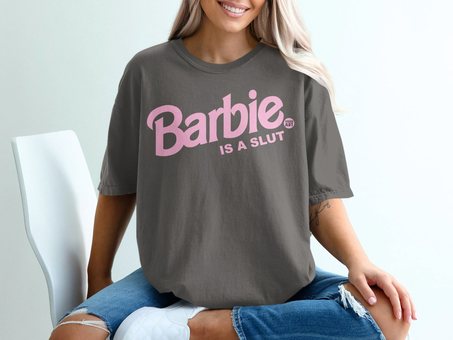 Dark grey t-shirt with "Barbie is a Slut" text in pink lettering.