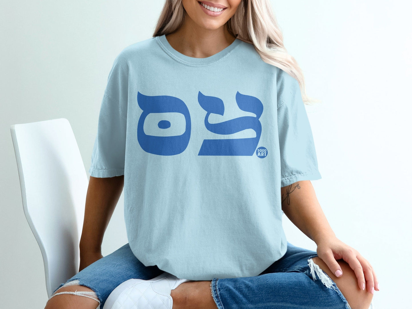 Light blue t-shirt with blue Hebrew text and a small "TODD ART" logo.
