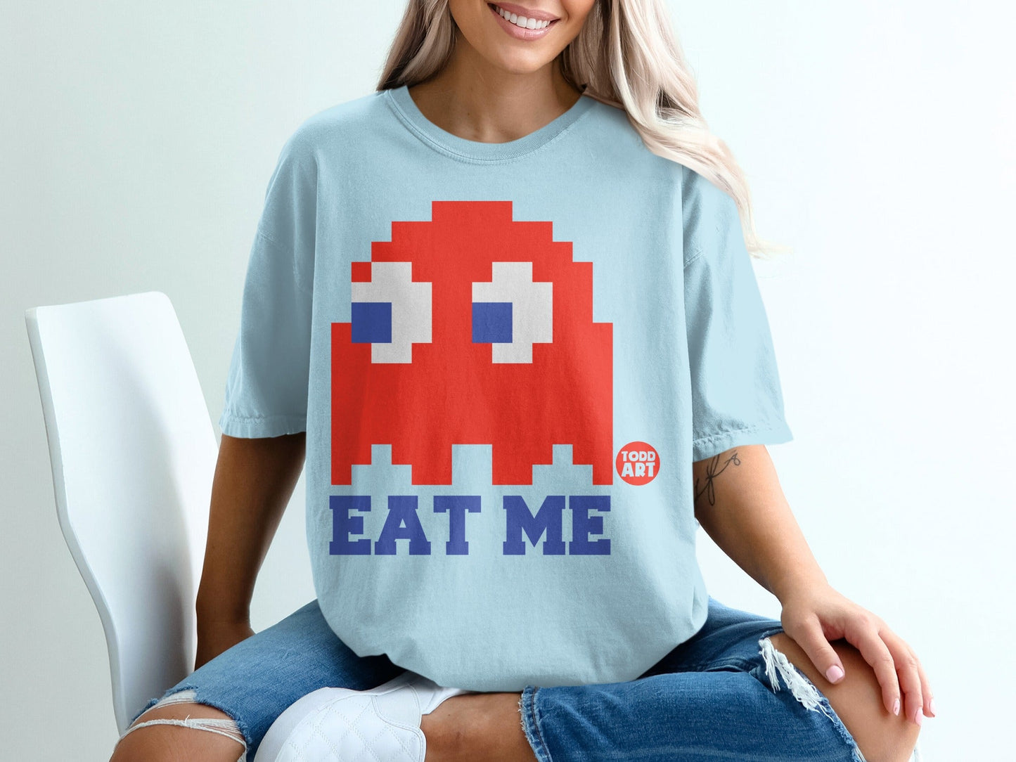 Light blue t-shirt with pixelated red ghost and "EAT ME" text.