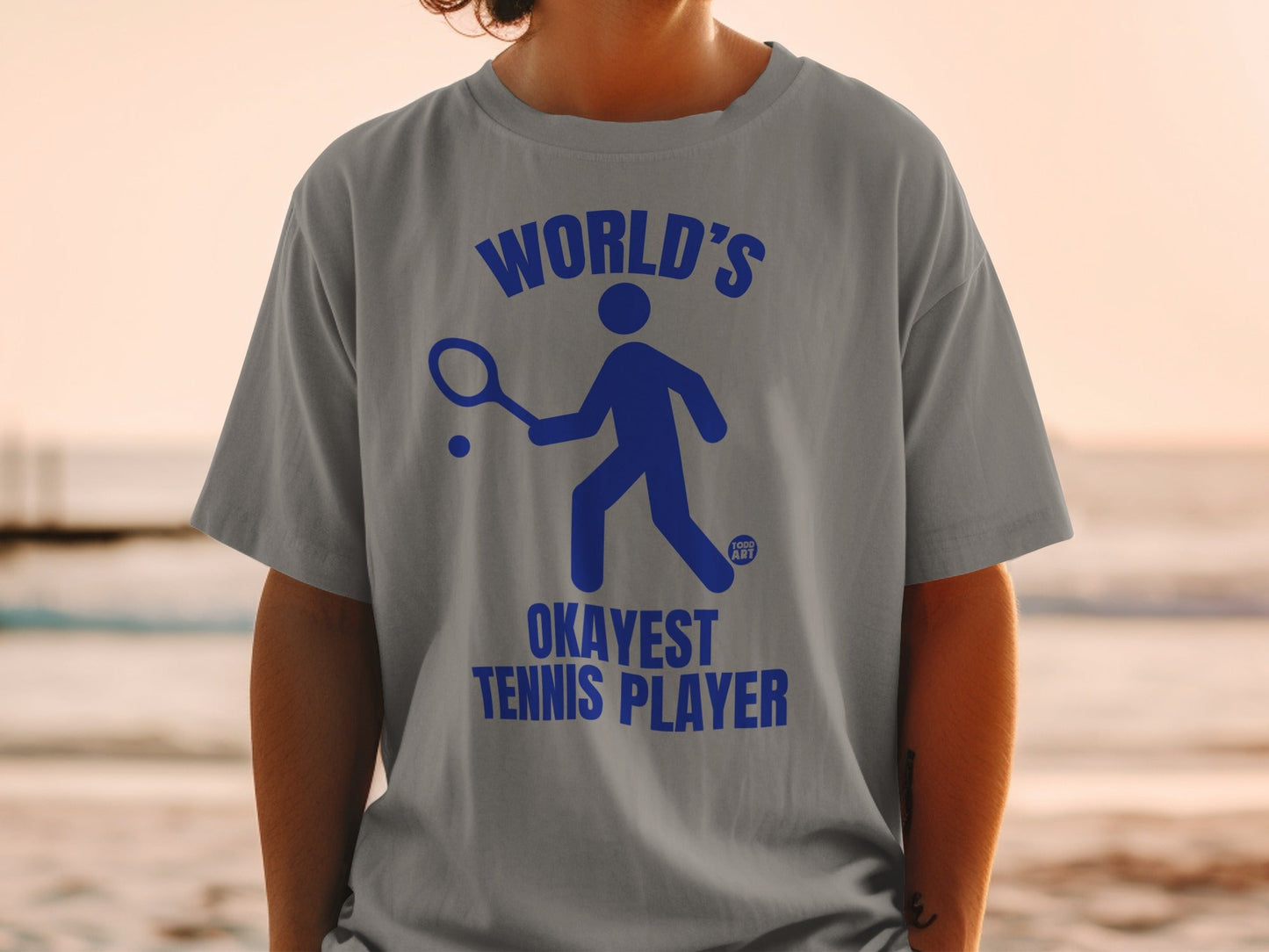 Gray t-shirt with blue "World's Okayest Tennis Player" text and icon.