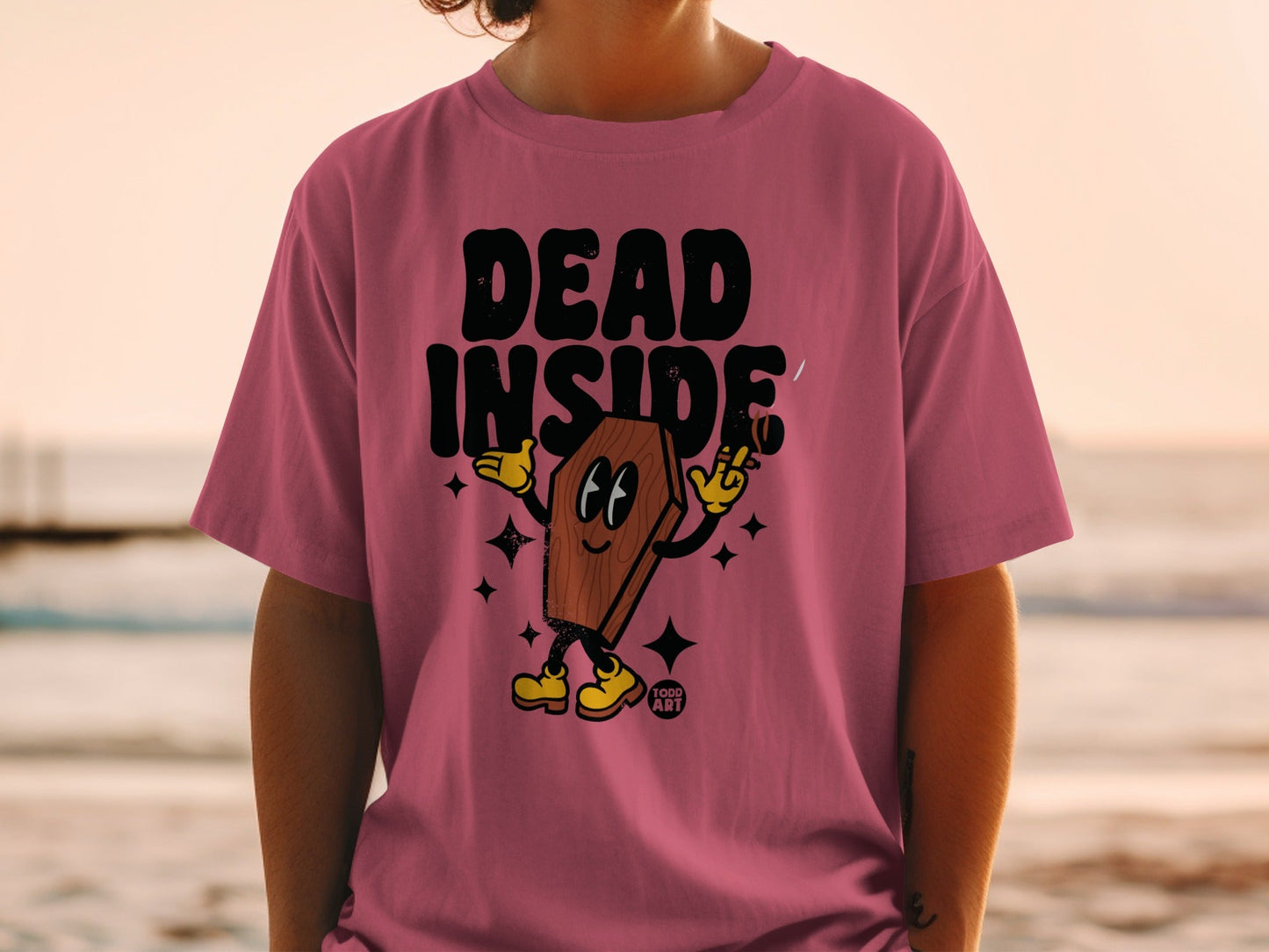Pink t-shirt with coffin character saying "DEAD INSIDE" and holding a cigarette.