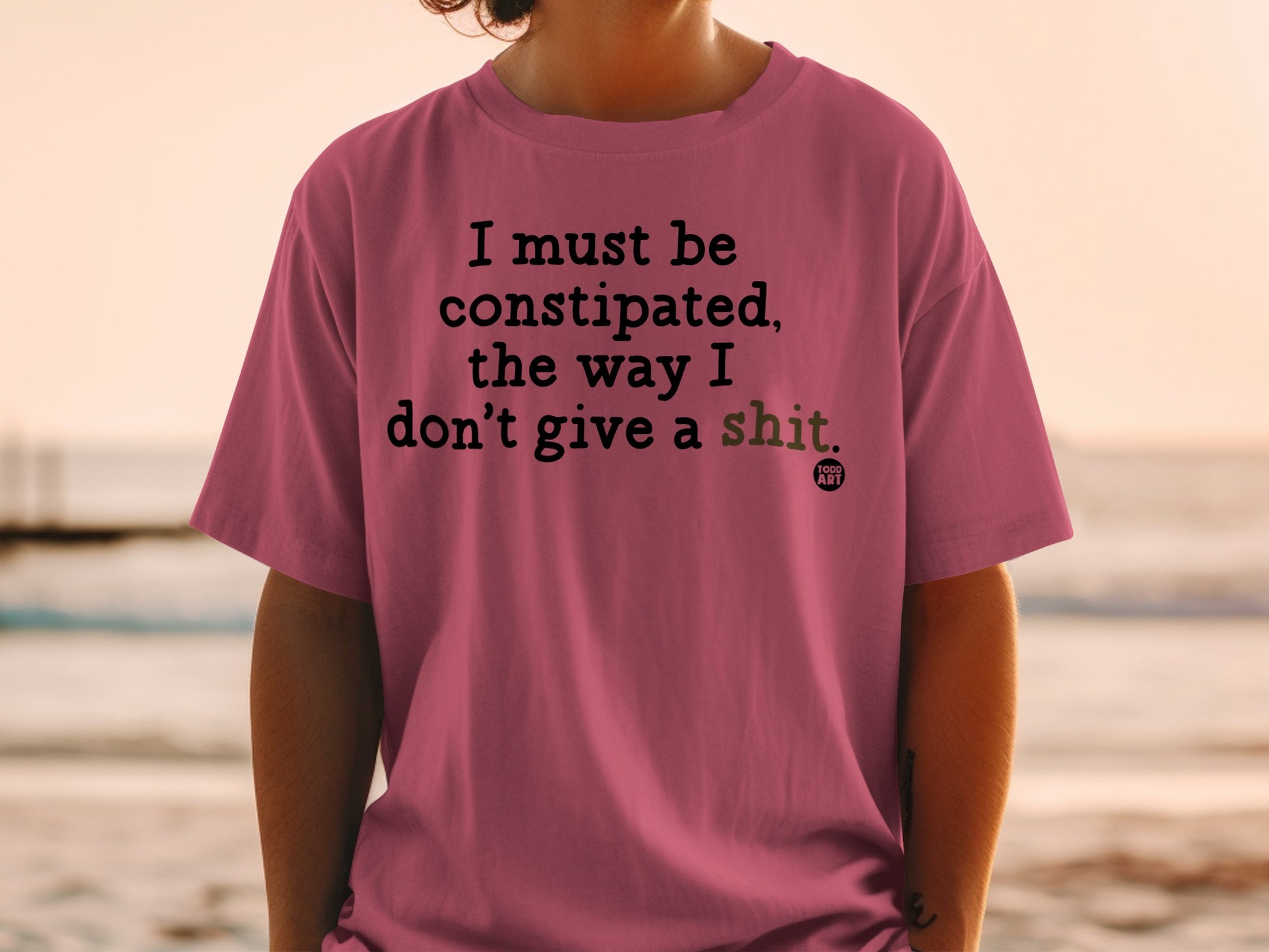 Pink t-shirt with "I must be constipated, the way I don't give a shit." text.
