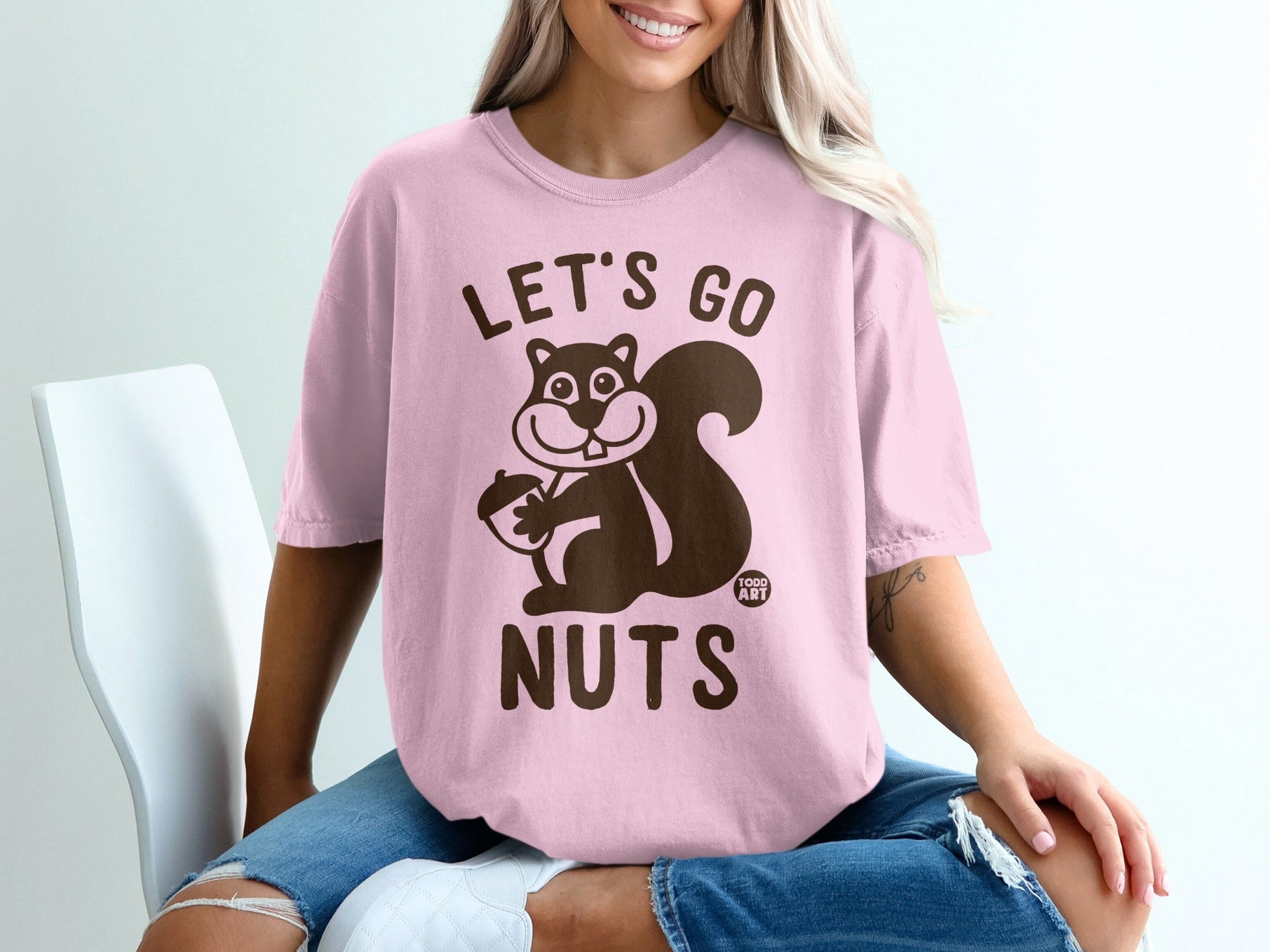 Pink t-shirt with "Let's Go Nuts" and a cartoon squirrel holding an acorn.