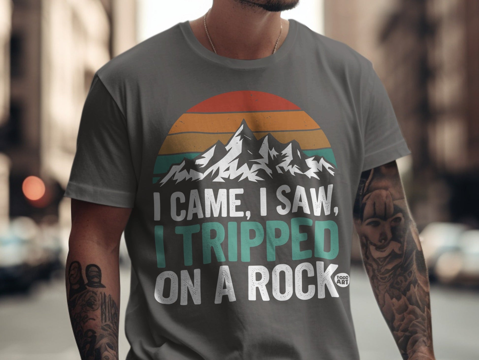 T-shirt with mountains, sunset, and text "I came, I saw, I tripped on a rock."