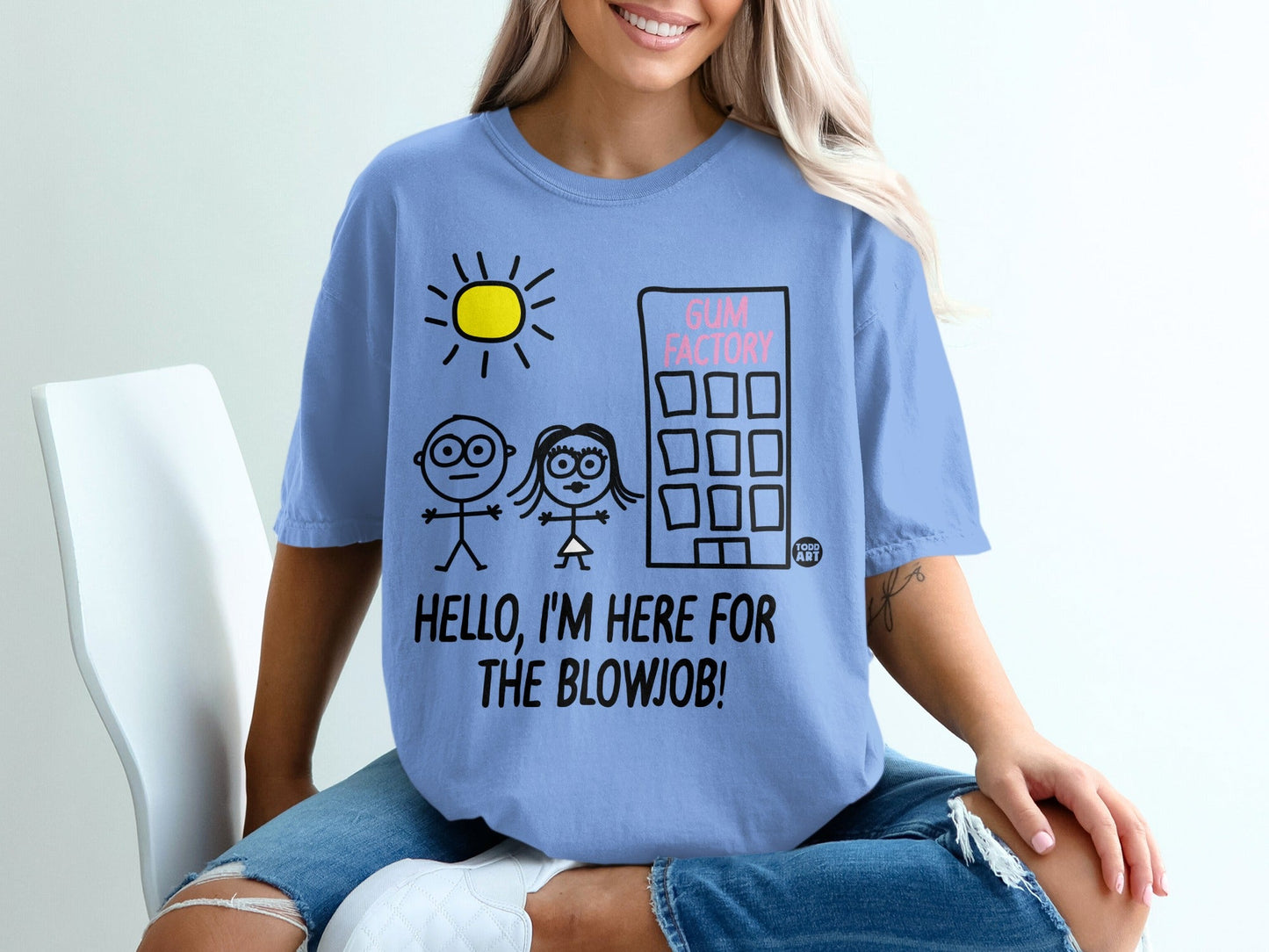 Blue t-shirt with "GUM FACTORY" graphic, sun, stick figures, and text.