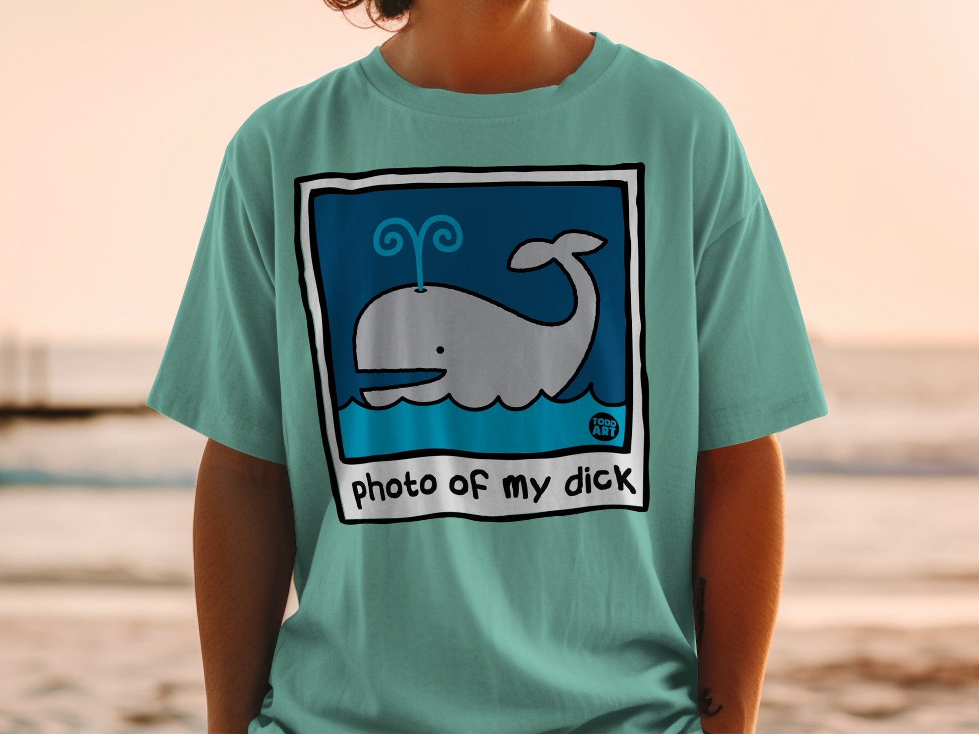 Teal t-shirt with a cartoon whale illustration and text "photo of my dick".