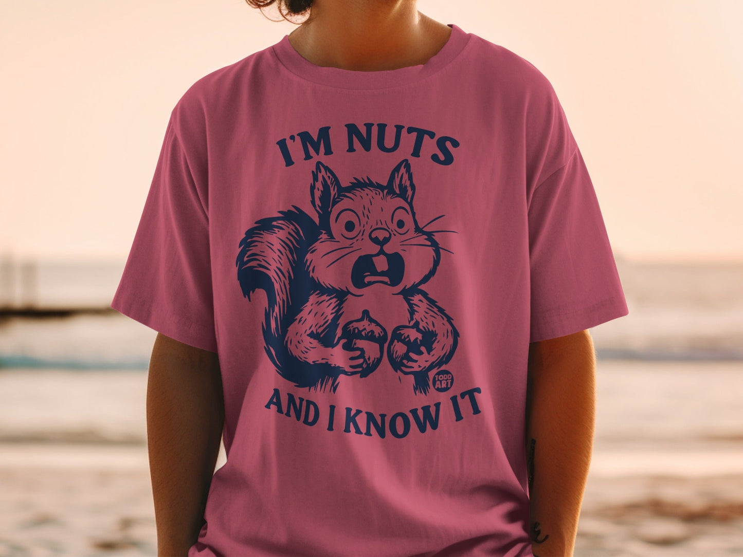 Pink t-shirt with navy graphic of a surprised squirrel saying "I'm nuts and I know it".