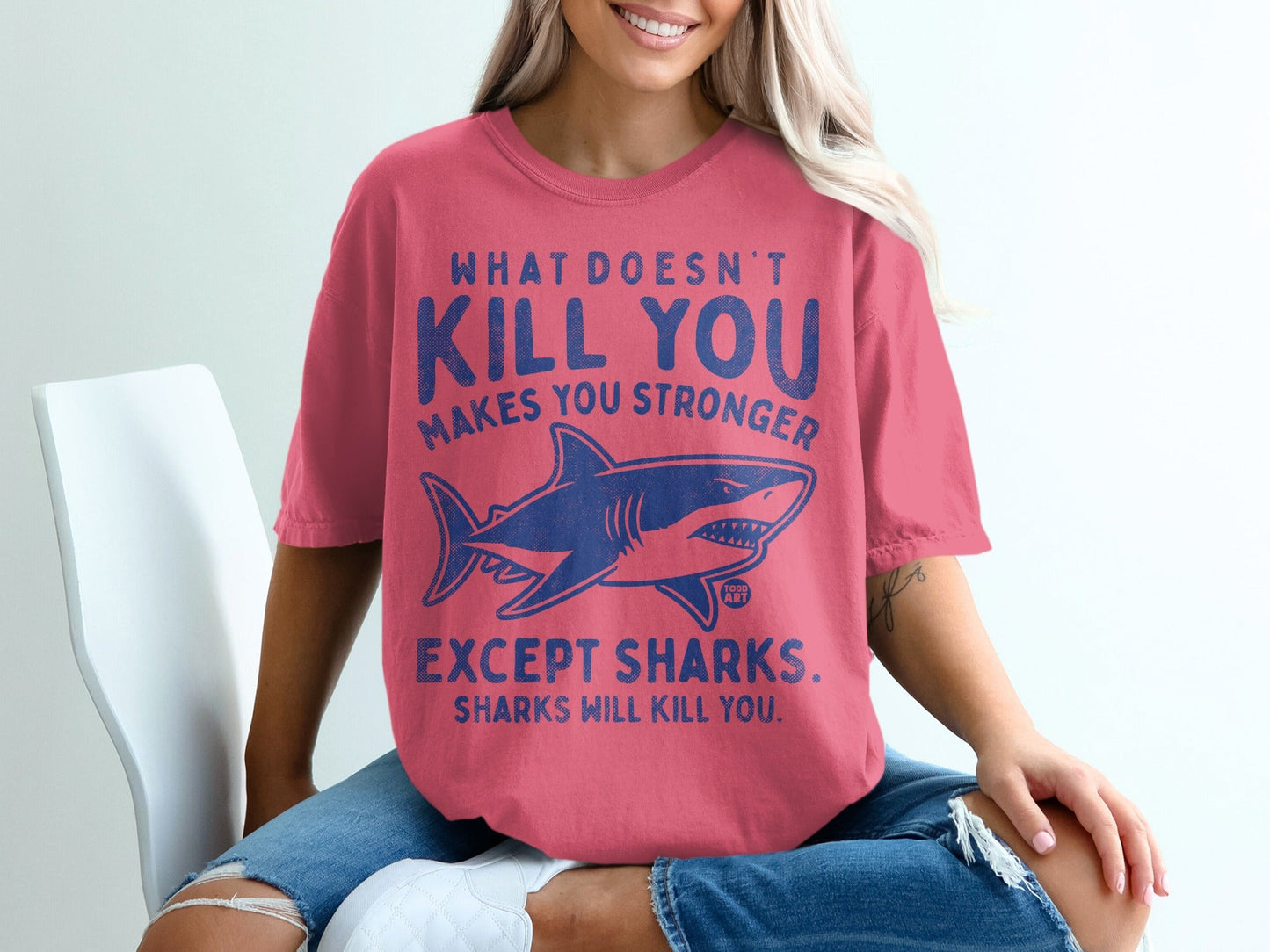 Pink t-shirt with blue shark graphic and text about sharks making you stronger.