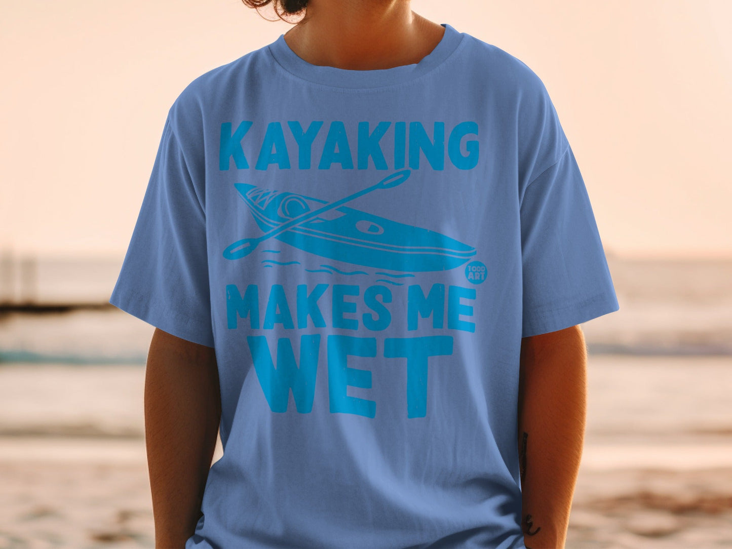 Blue t-shirt with a kayak and "Kayaking Makes Me Wet" text.