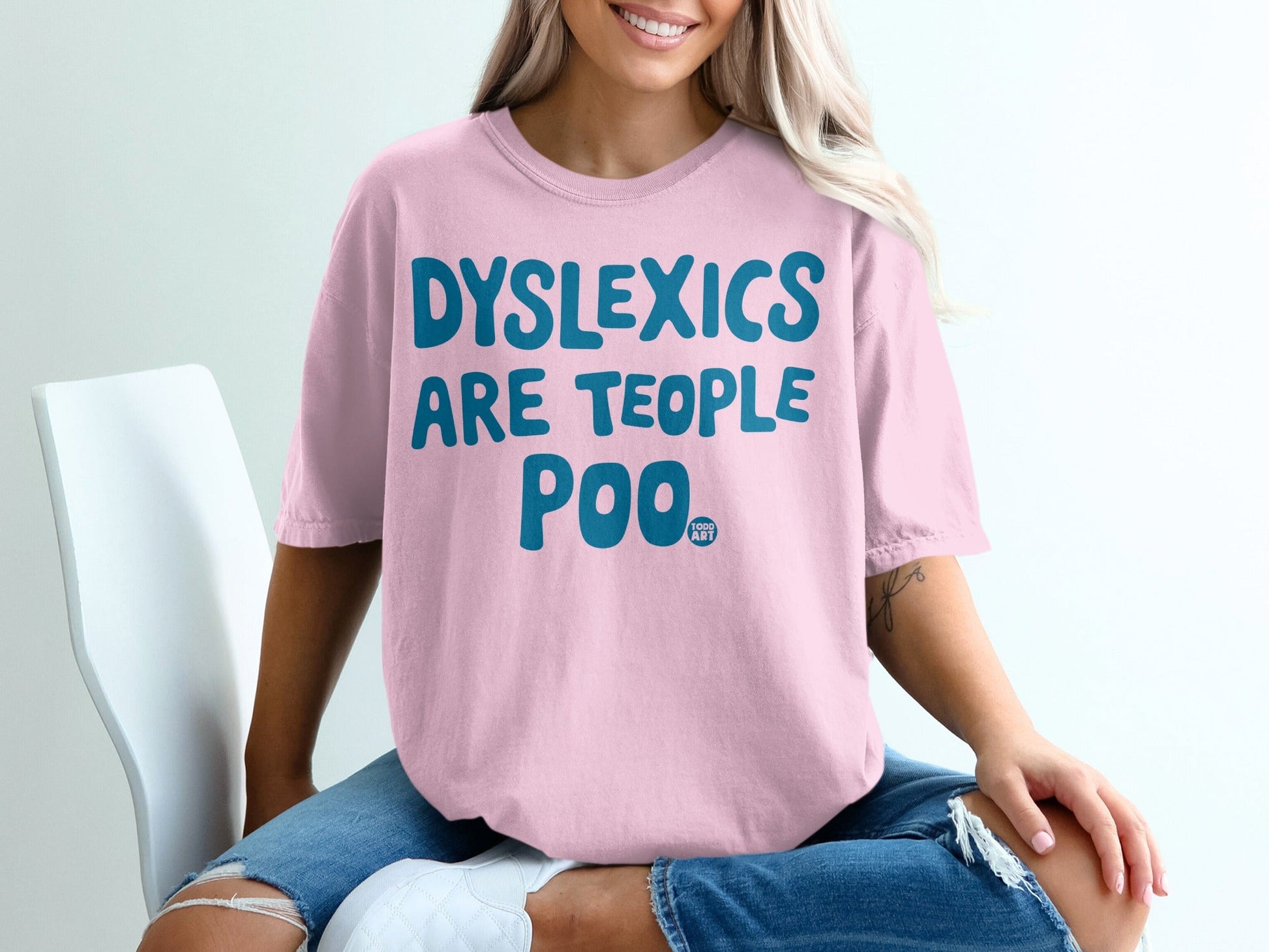 Pink t-shirt with blue text reading "DYSLEXICS ARE TEOPPLE POO".