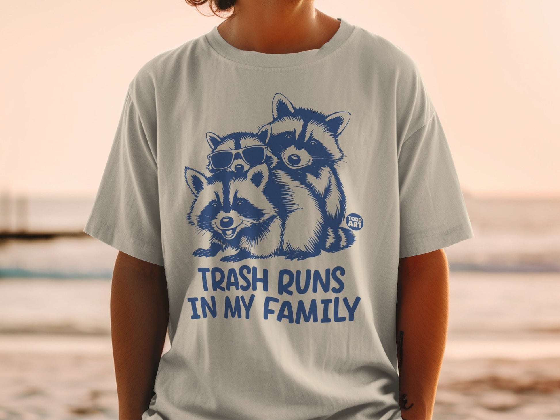 T-shirt with three raccoons wearing sunglasses, text "TRASH RUNS IN MY FAMILY".
