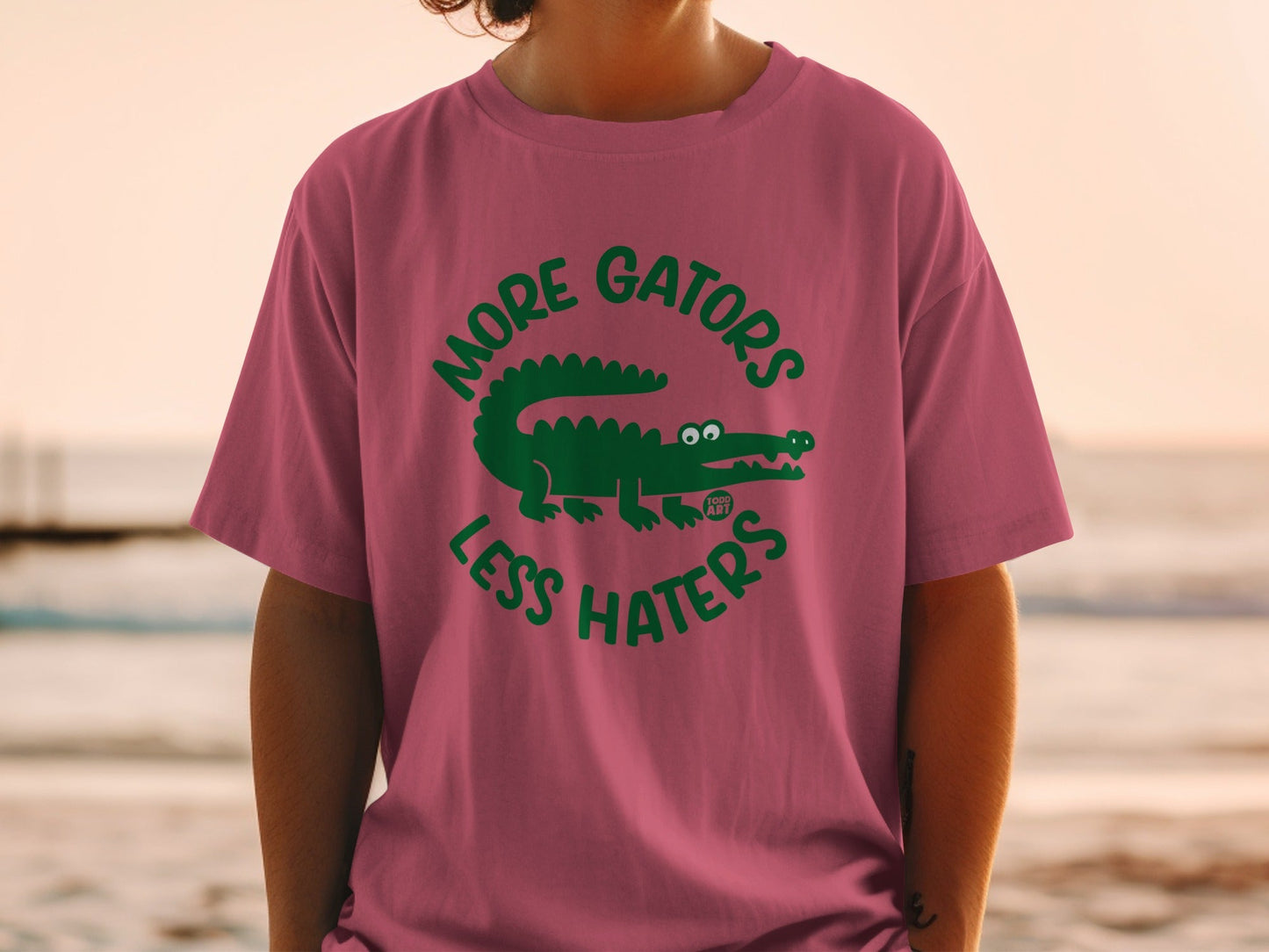 Pink t-shirt with green "More Gators Less Haters" alligator graphic.