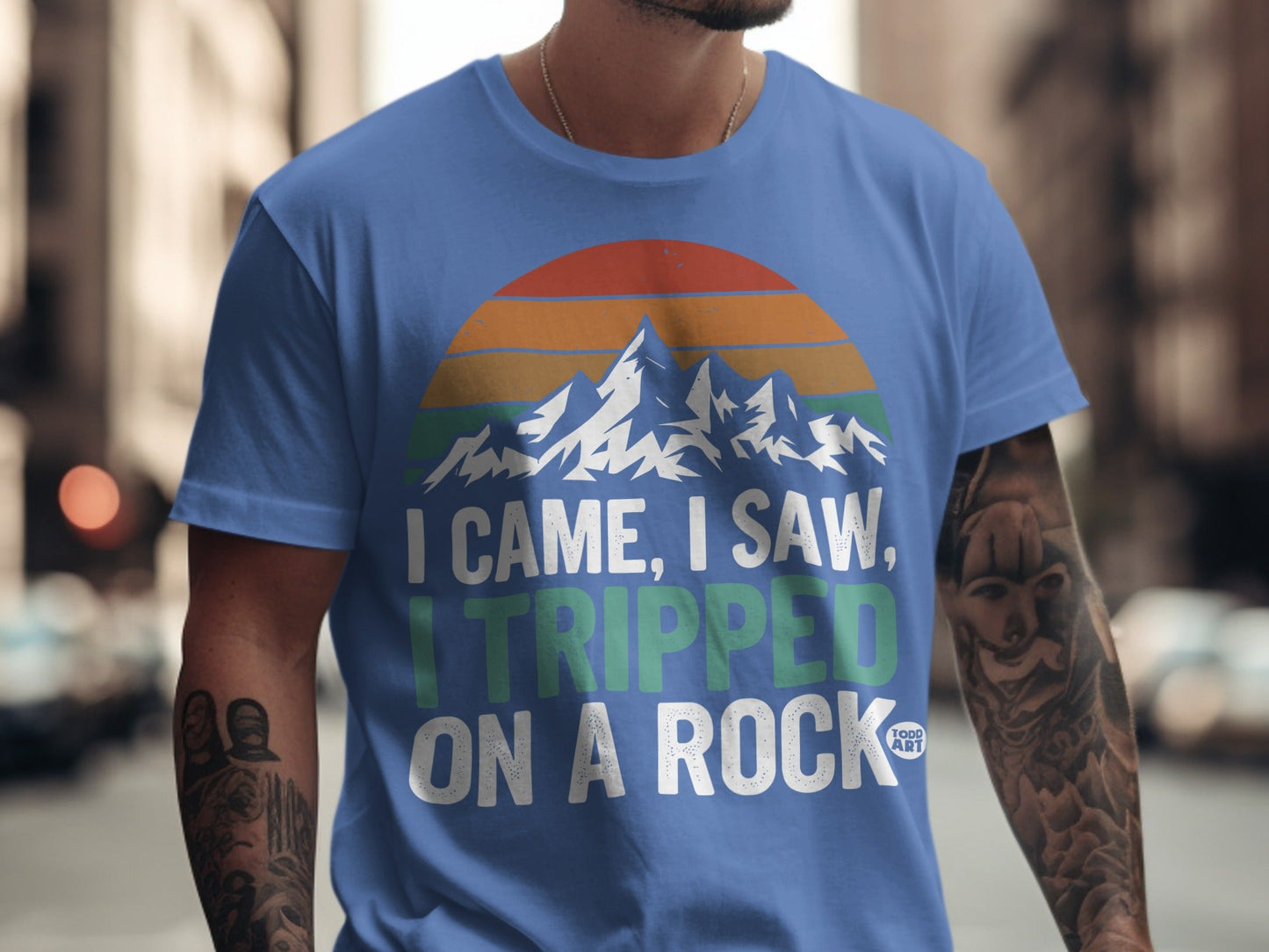 Blue t-shirt with mountains and text: "I came, I saw, I tripped on a rock."