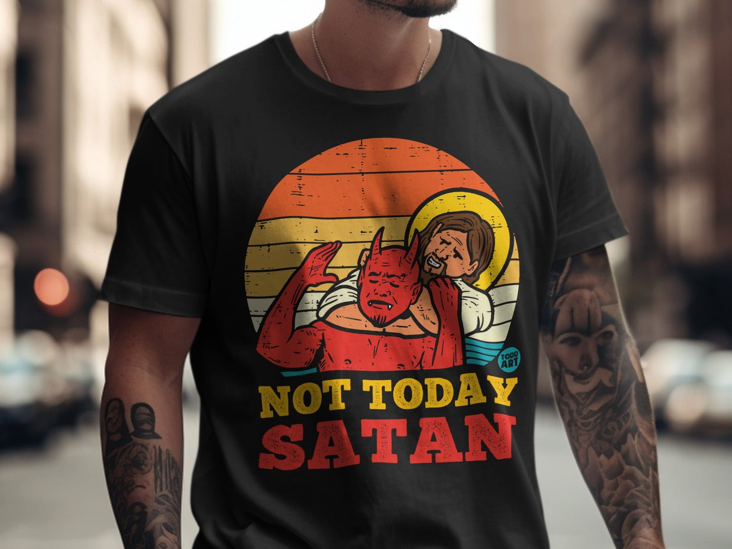 Graphic tee with Jesus pushing Satan away in a sunset circle.
