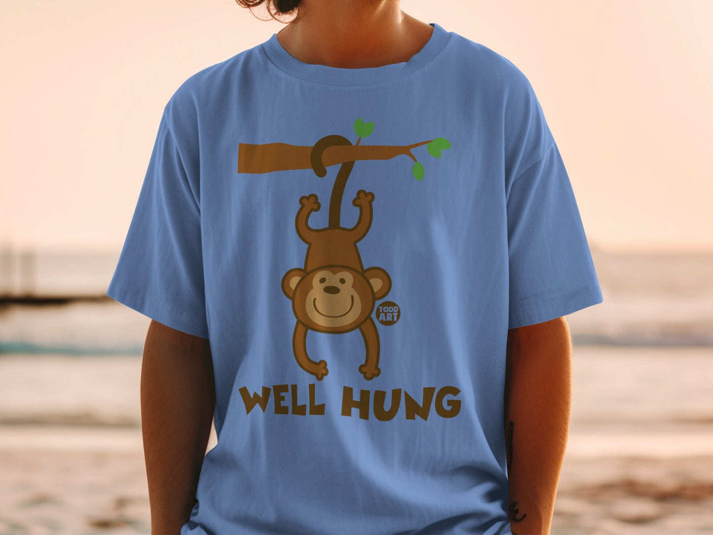 Blue t-shirt with a cartoon monkey hanging from a branch, text reads "WELL HUNG".